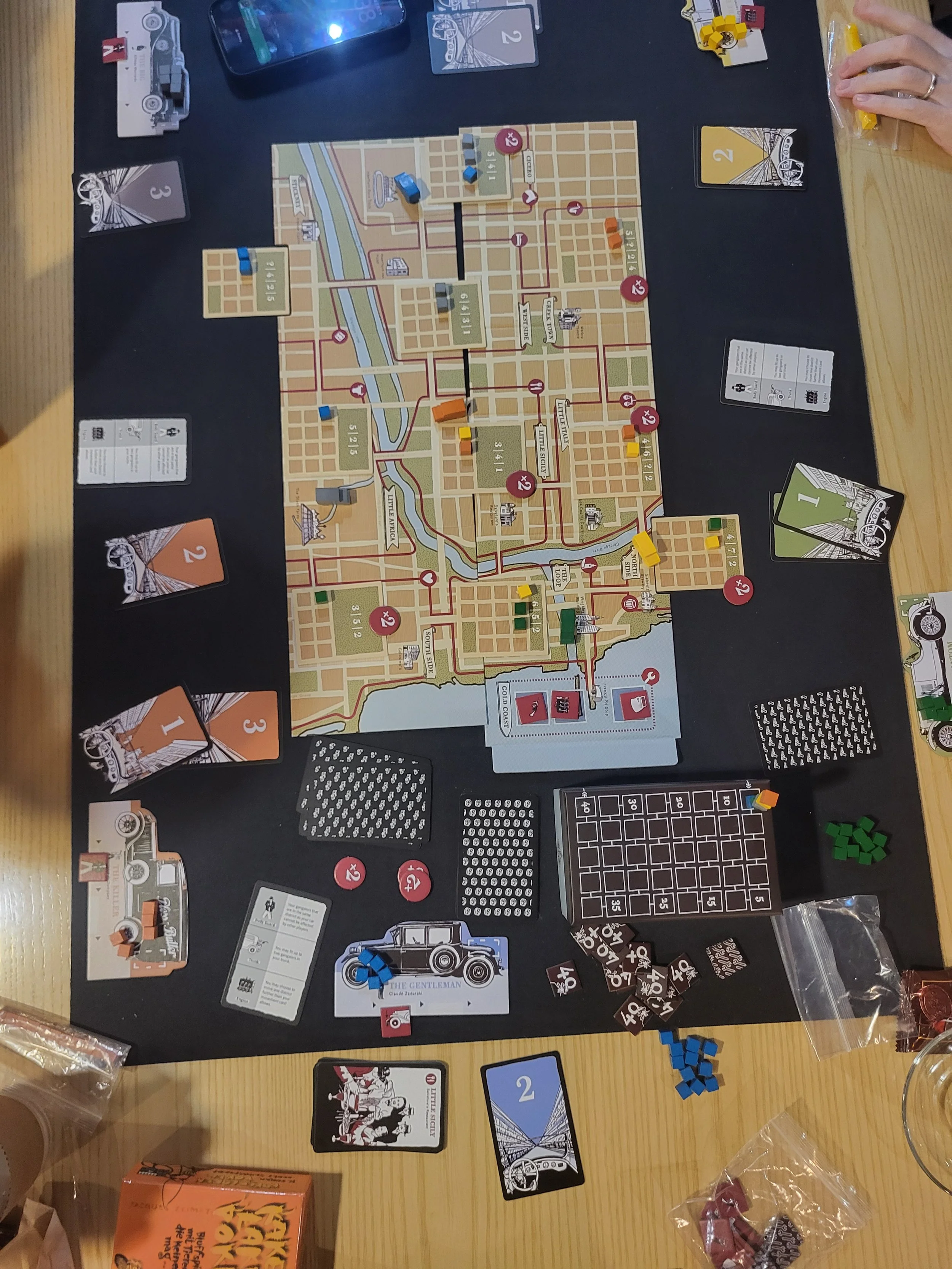 Photo of the Gangster board from above - there are cards for movement, and little wooden cubes and cars moving around the board.
