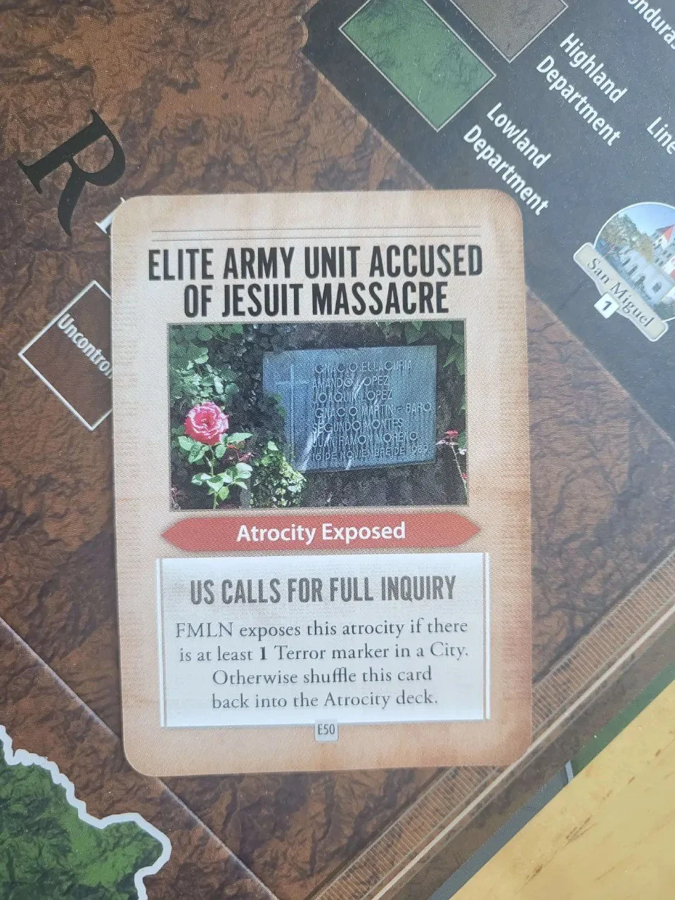 A close up photo of an atrocity card. It is titled Elite Army Unit Accused of Jesuit Massacre and shows a picture of a grave stone.