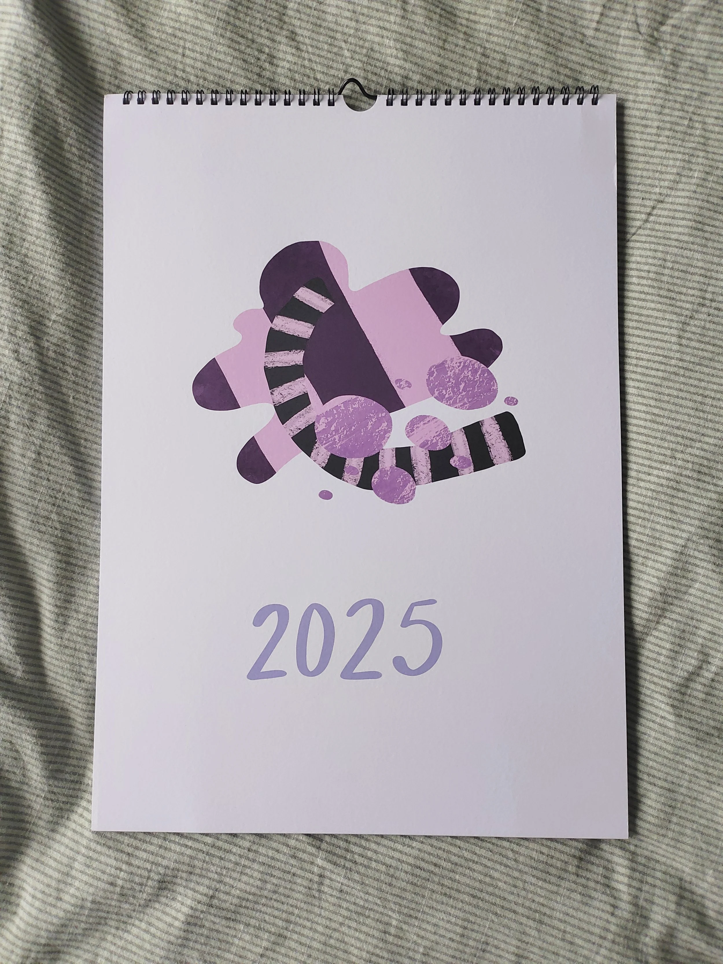 Kalenteri vuodelle 2025, jossa on abstrakti, värikkäitä muotoja.