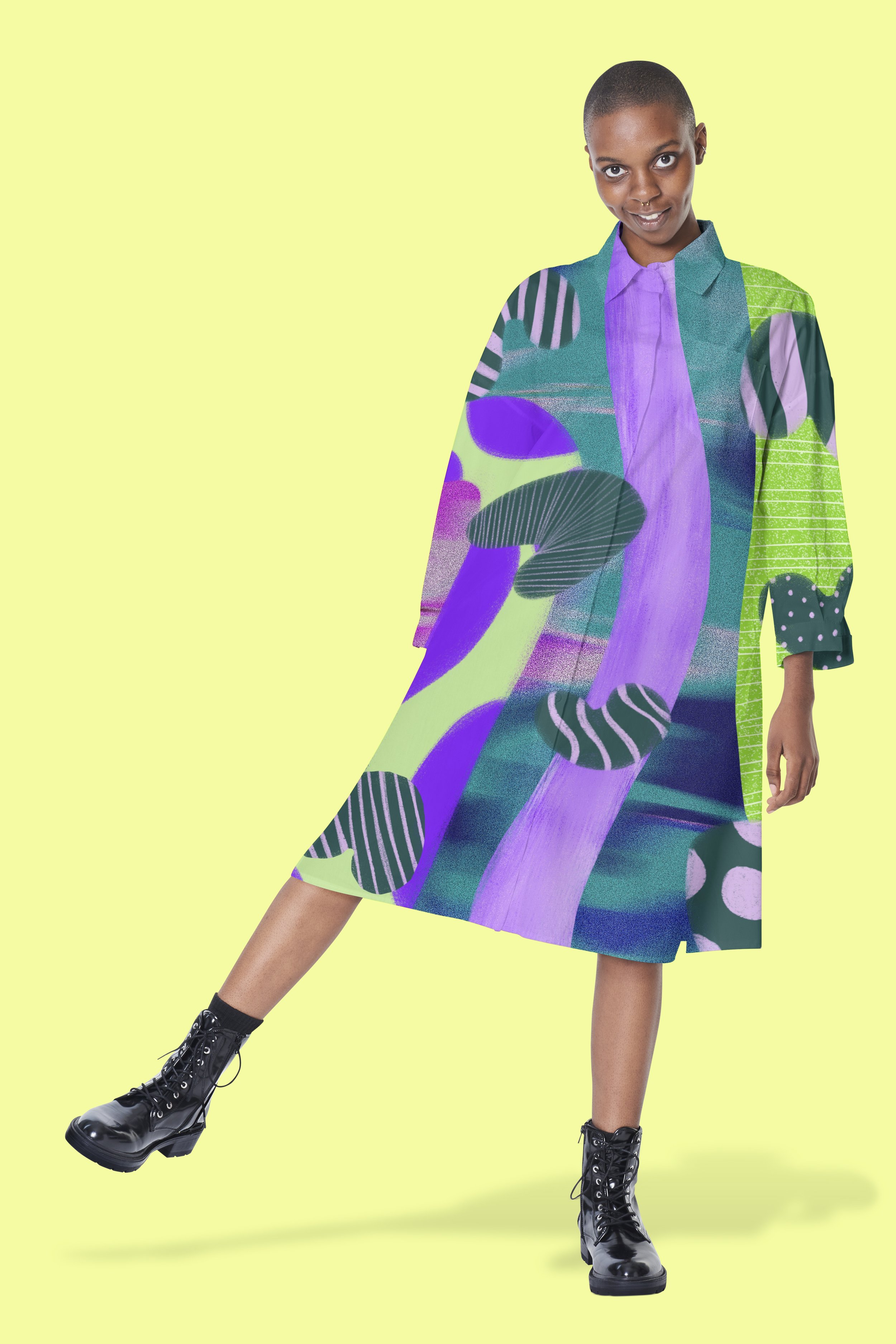 A woman wearing a multicolored, abstract-patterned dress with black lace-up boots, standing against a yellow background.