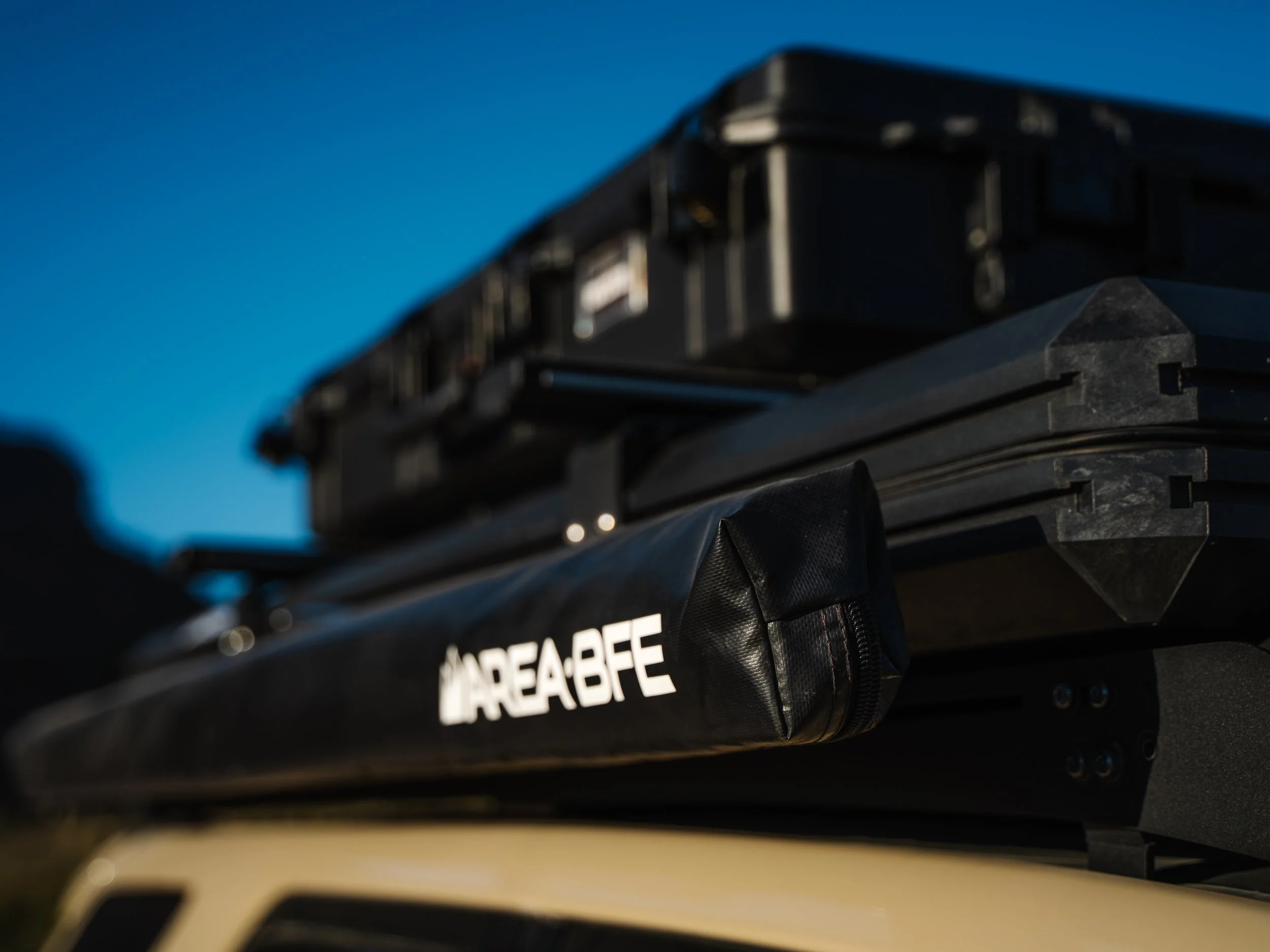 Close-up of a black rooftop equipment with a white label that reads 'AREA BFE' on a vehicle, with a clear blue sky in the background.