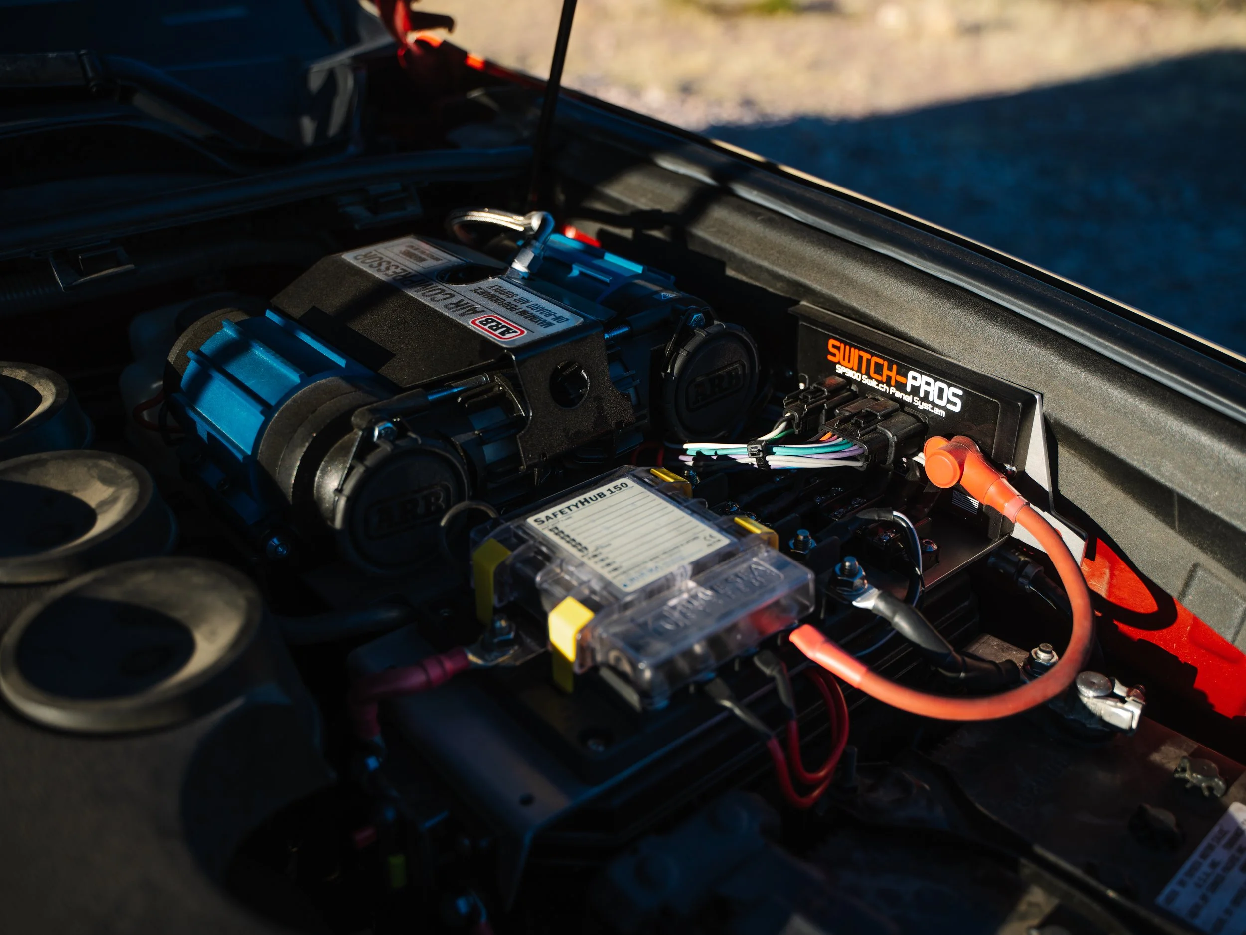 Close-up of an electric vehicle's engine bay showing high-performance components and wiring, with sunlight illuminating the setup.