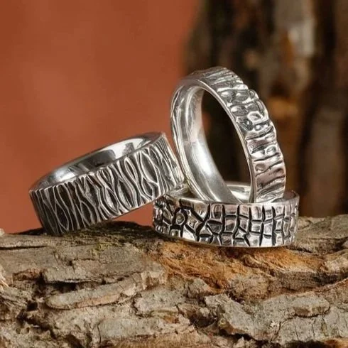 Three sterling silver rings with the texture from three different trees represented; flowering dogwood, ginkgo, and wood grain.