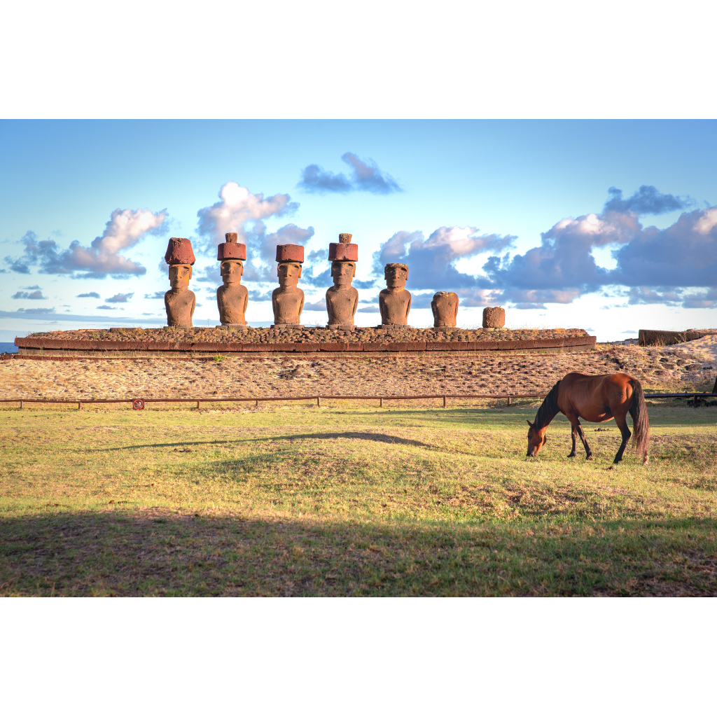 Moai statues at sunrise on Easter Island at Ahu Nau Nau with a horse grazing in the foreground