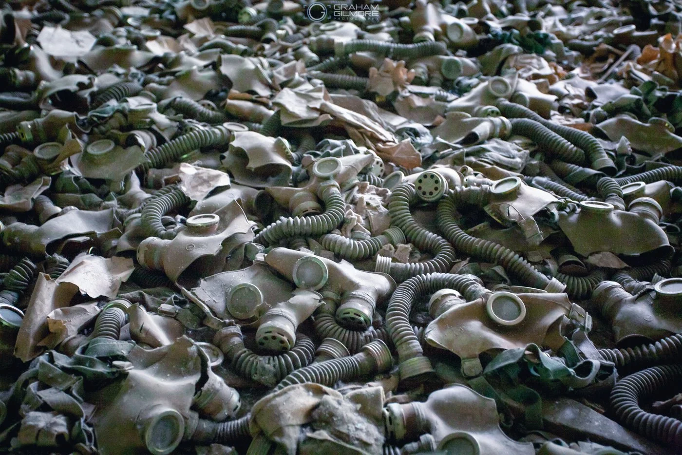 A large pile of discarded gas masks and breathing apparatuses on the ground.