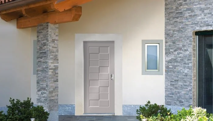 Porta di ingresso moderna con pareti in pietra e finestra su una facciata di casa.