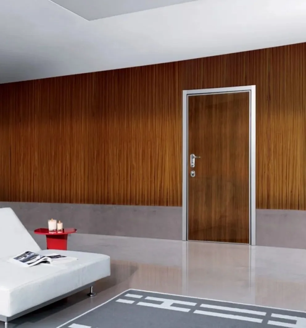 Interno moderno con pareti di legno, porta in legno con cornice di metallo, divano bianco, tavolino rosso con candele e rivista.