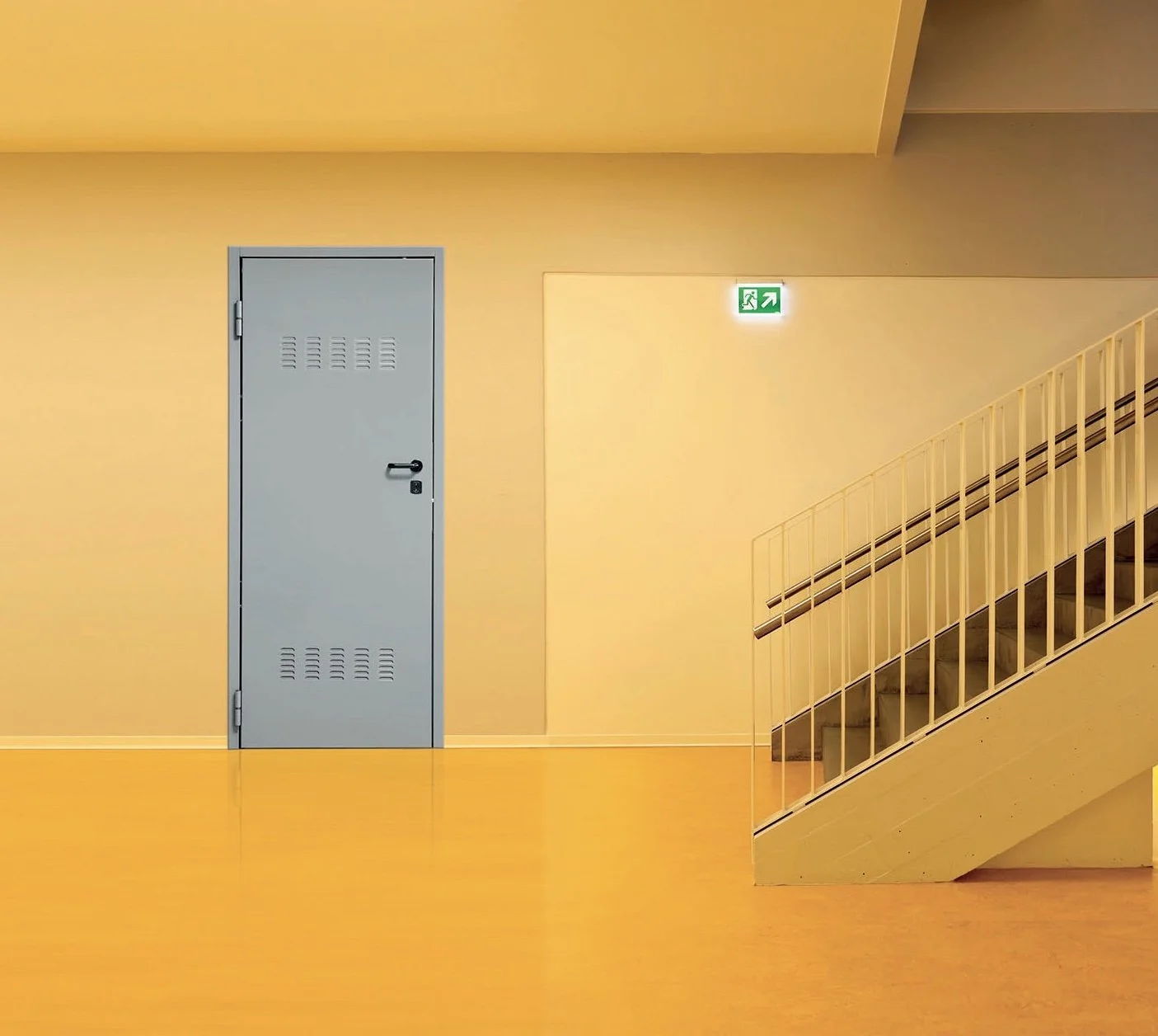Parete gialla con porta blu e scala bianca con ringhiera, con segnale di uscita di emergenza verde.