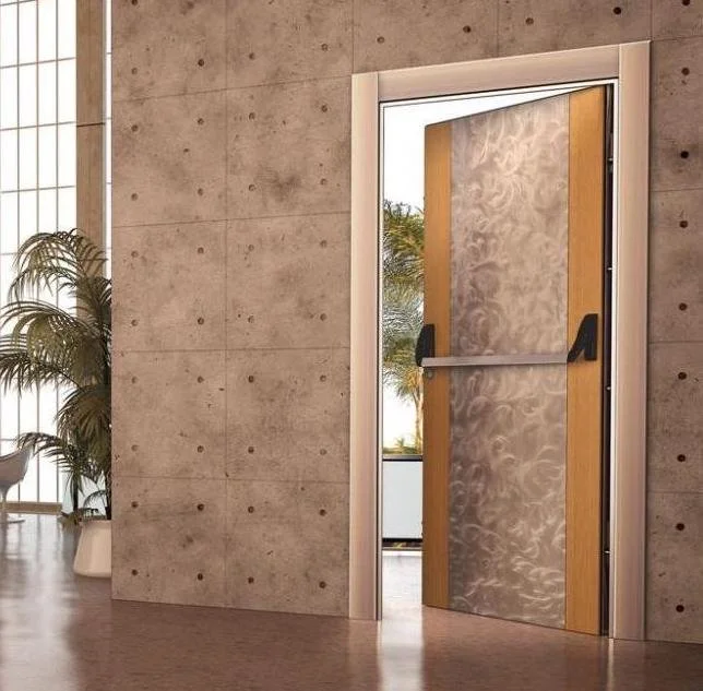 Porta con vetro di sicurezza parzialmente aperta in un edificio moderno con pareti in cemento e piante verdi sullo sfondo.