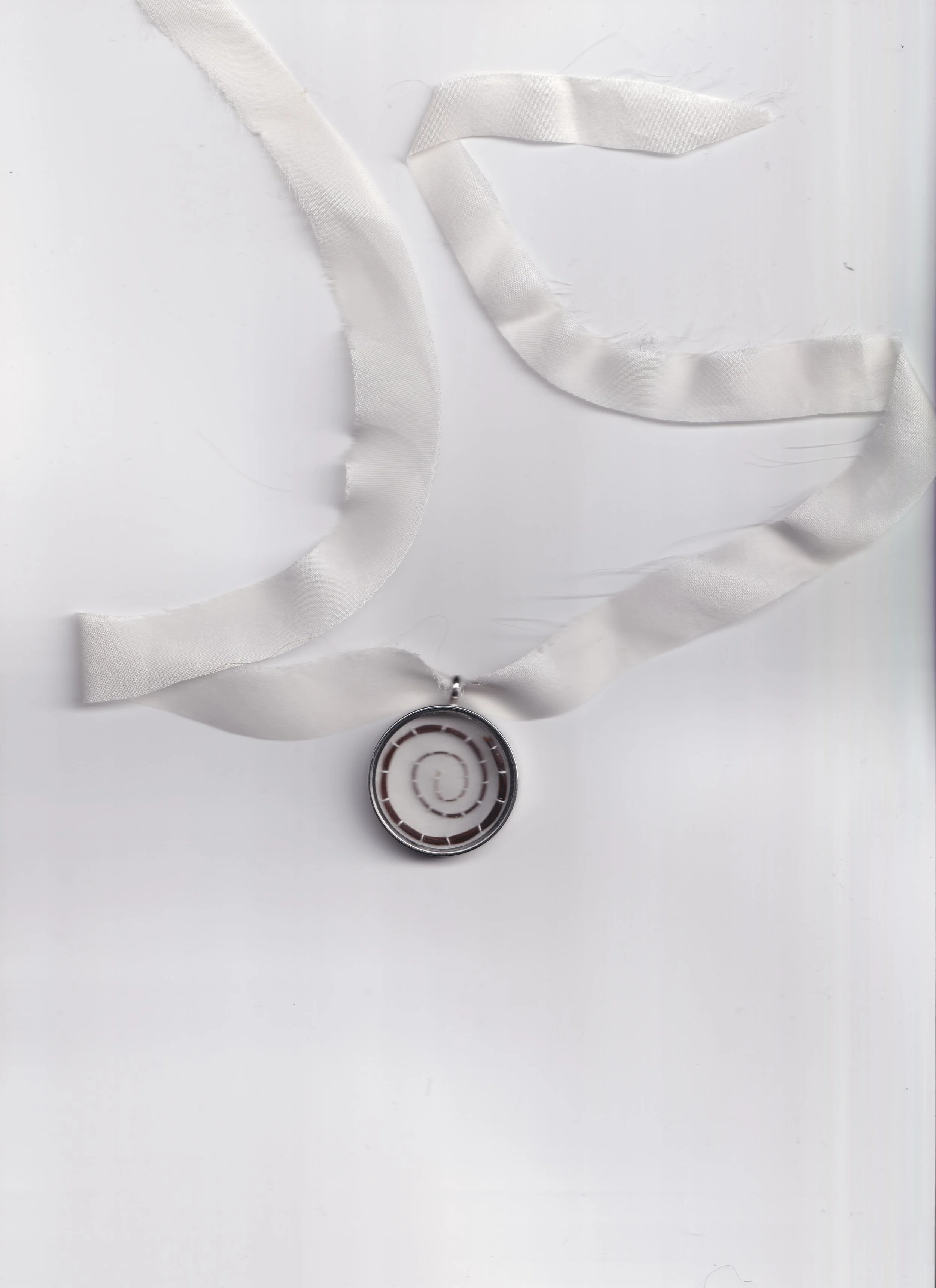 A spiral pendant necklace with a white ribbon chain on a white background.