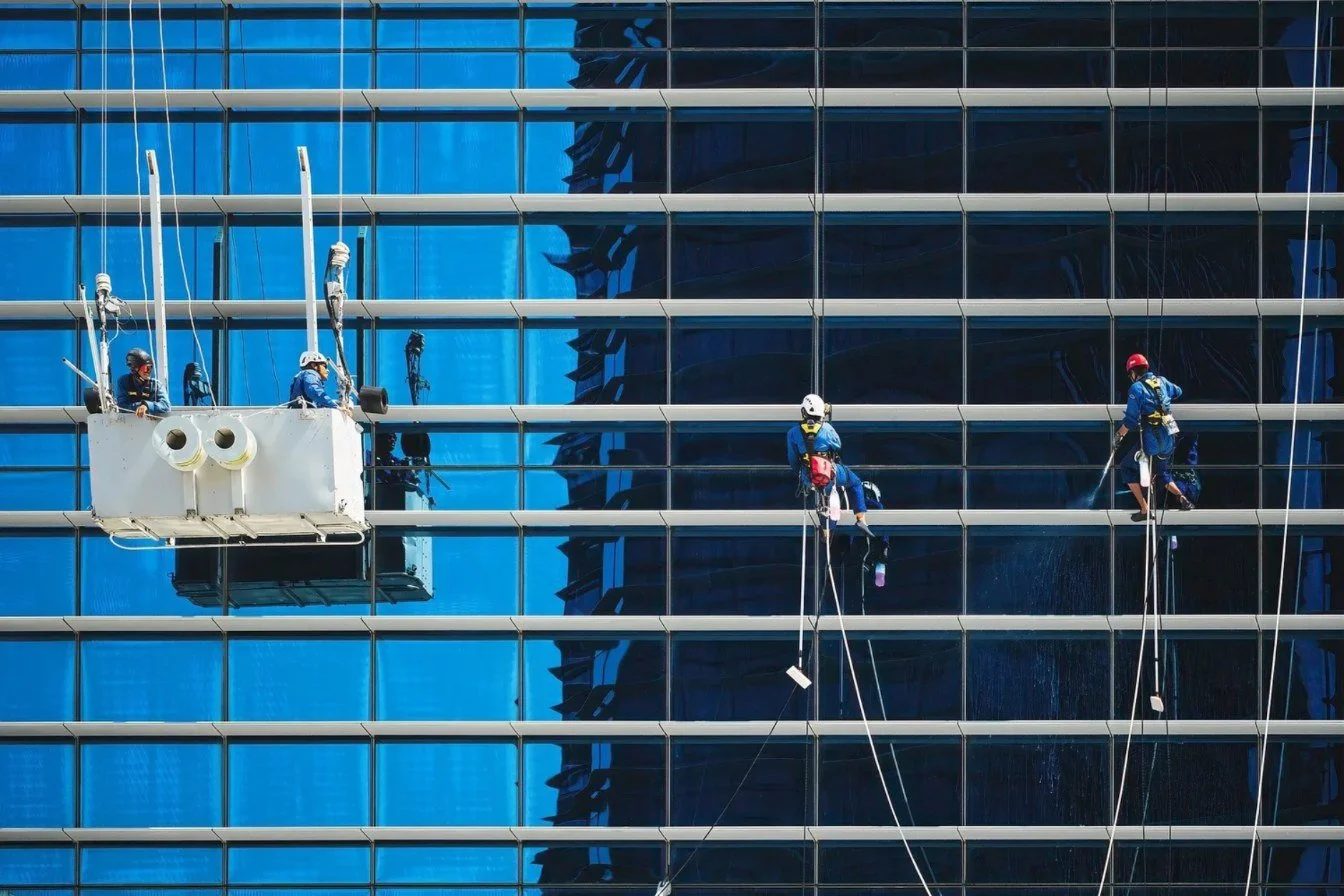 Window cleaners using a cradle and rope access on a glass high-rise facade
