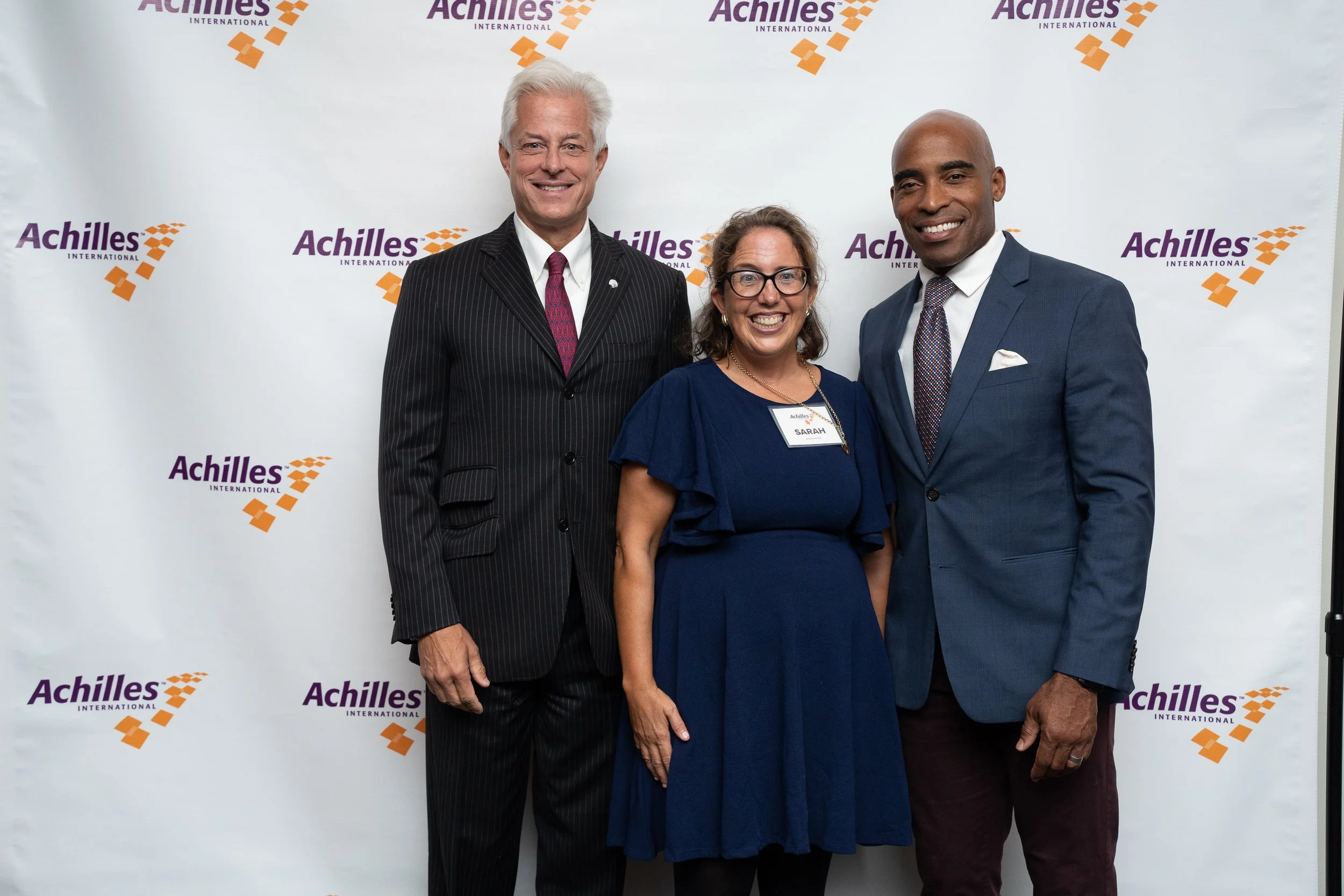 Tiki Barber poses with honorees Sarah Heller and Ross Moody in front of Achilles branded step and repeat  