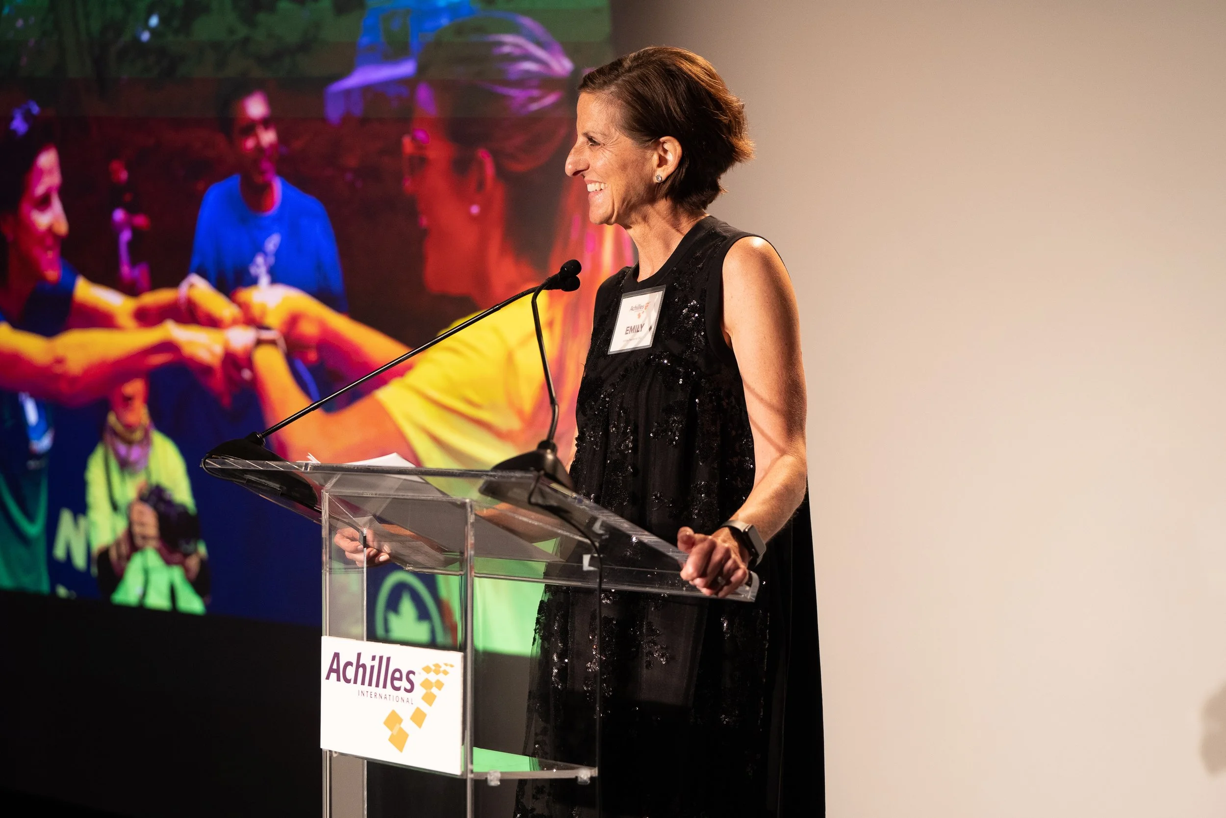  President and CEO Emily Glasser smiles while standing at podium during program  