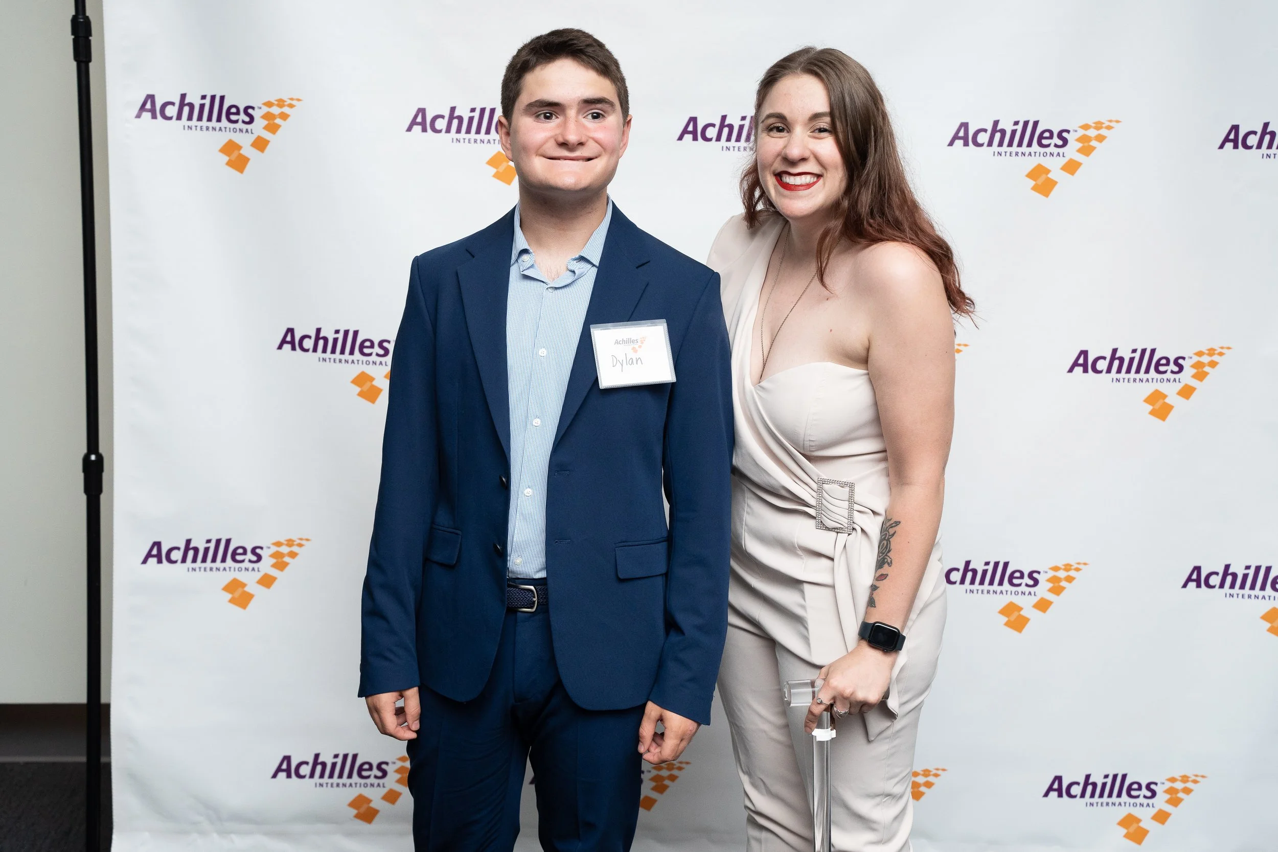  Team Achilles kid member poses with program manager Lindsey Novakovic in front of Achilles branded step and repeat 