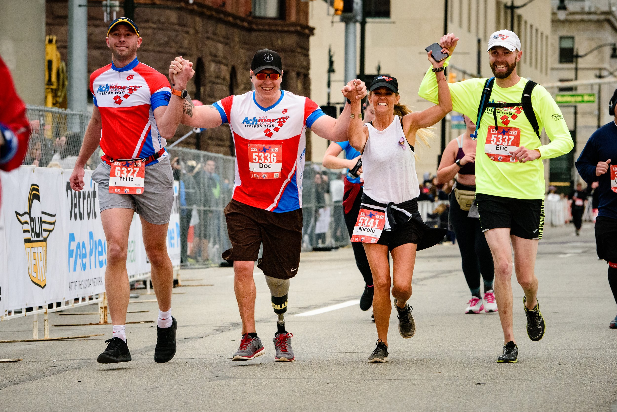  Photo of Freedom Team members holding hands and crossing the finish line at the 2021 Detroit Marathon 