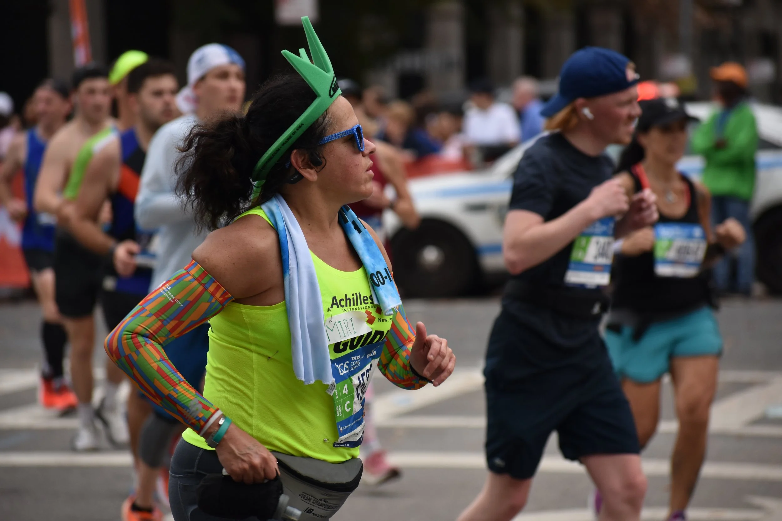  Women wearing sunglasses and a crown resembling the Statue of Liberty’s running passed Engineer’s Gate and the NYC Marathon 