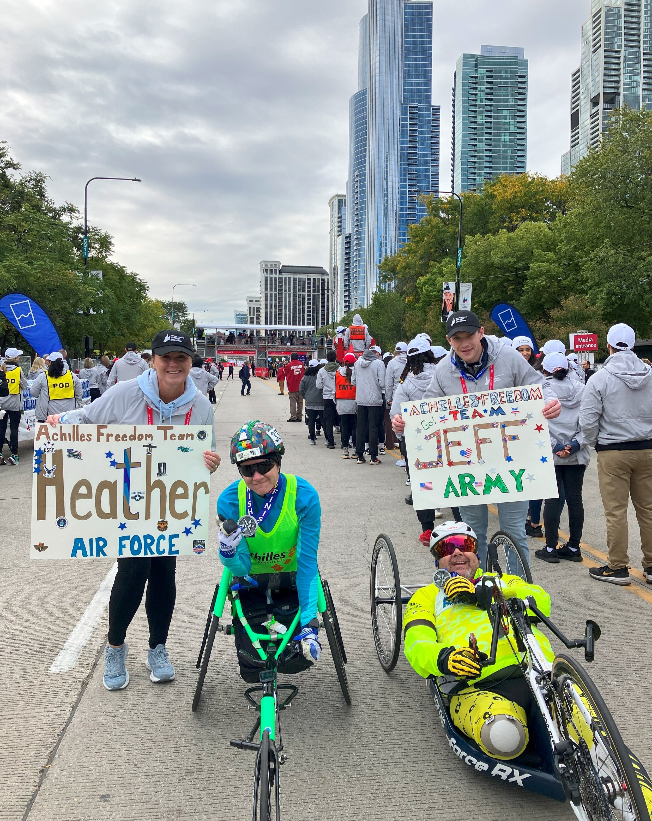  Achilles Freedom Team members, Heather and Jeff, posing with hand made signs cheering them on 