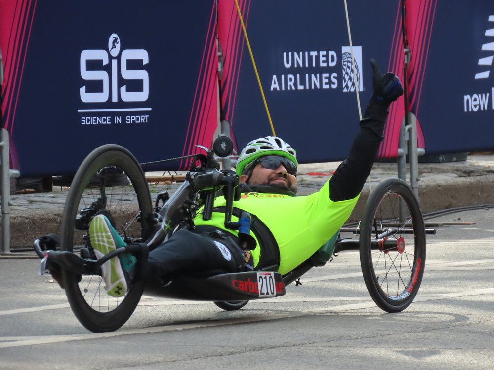  Achilles athlete posing with a thumbs up on his handcycle  