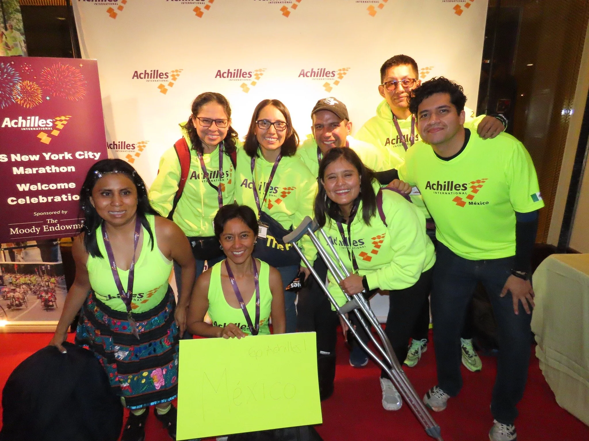 Group shot of members of Achilles Mexico in front of an Achilles branded step and repeat