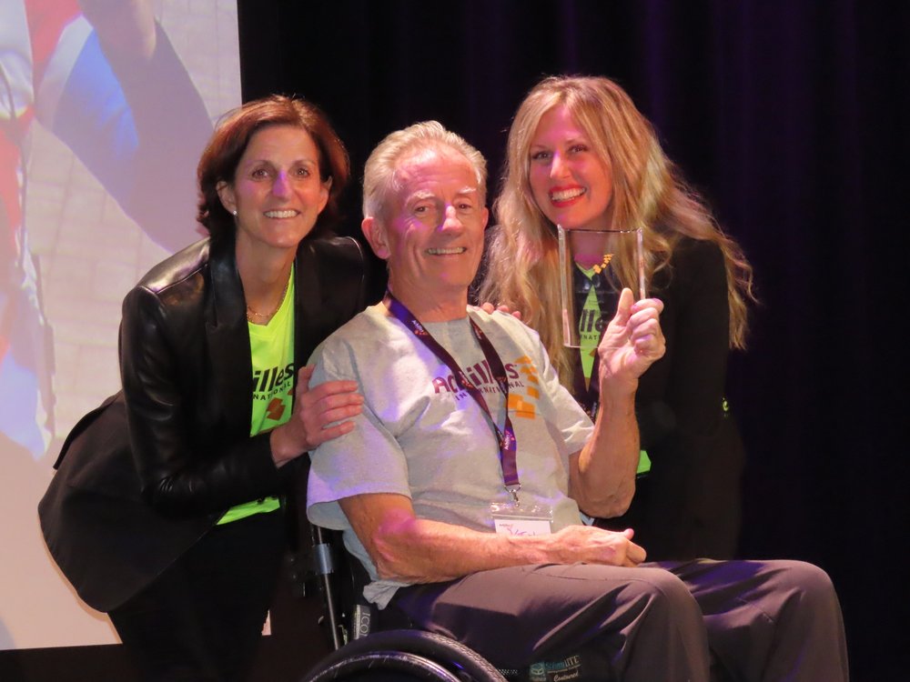  Ken Higgins of the Achilles Freedom Team accepting his award next to Emily Glasser and Janet Patton, Achilles Vice President of Event Production and Expansion  