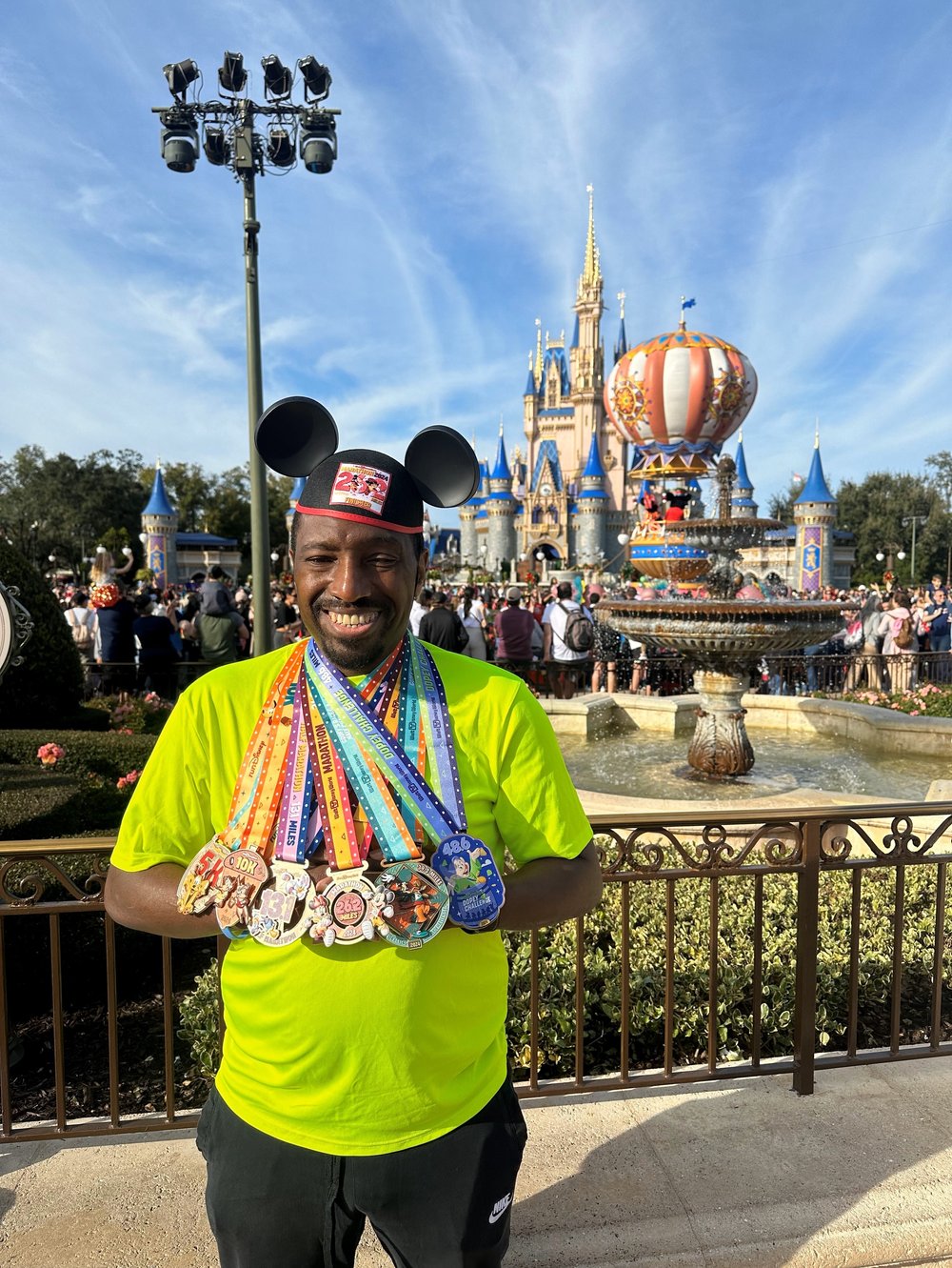 Achilles member smiling in front of the Castle wearing all of his medals from the Dopey Challenge 