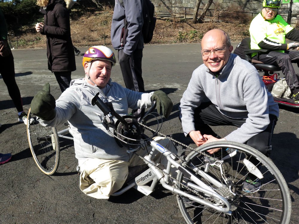  Dick Traum posing on his handcycle next to an Achilles athlete  