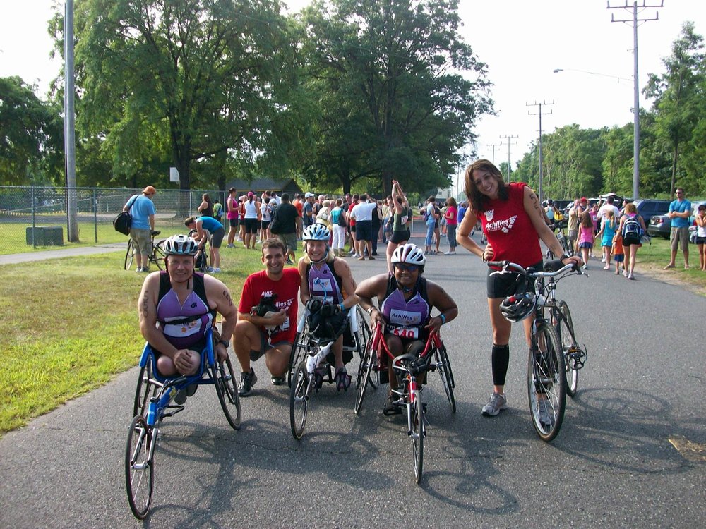  Minda smiling and posing in her racing wheelchair with other members of TriAchilles in 2008 
