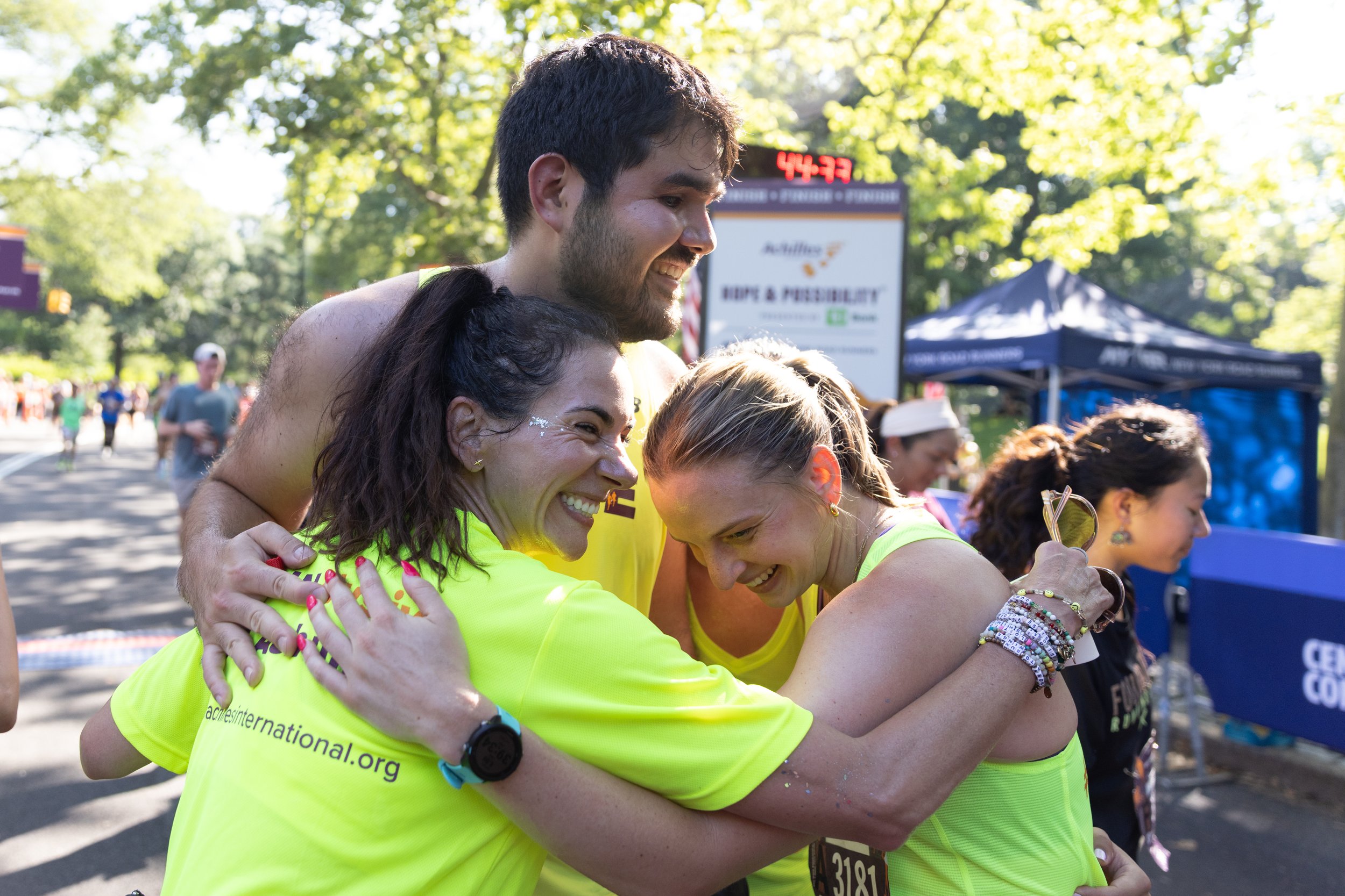 Mariana Fernández, Francesco Magisano and Achilles guide Marissa hugging after crossing the finish line together.