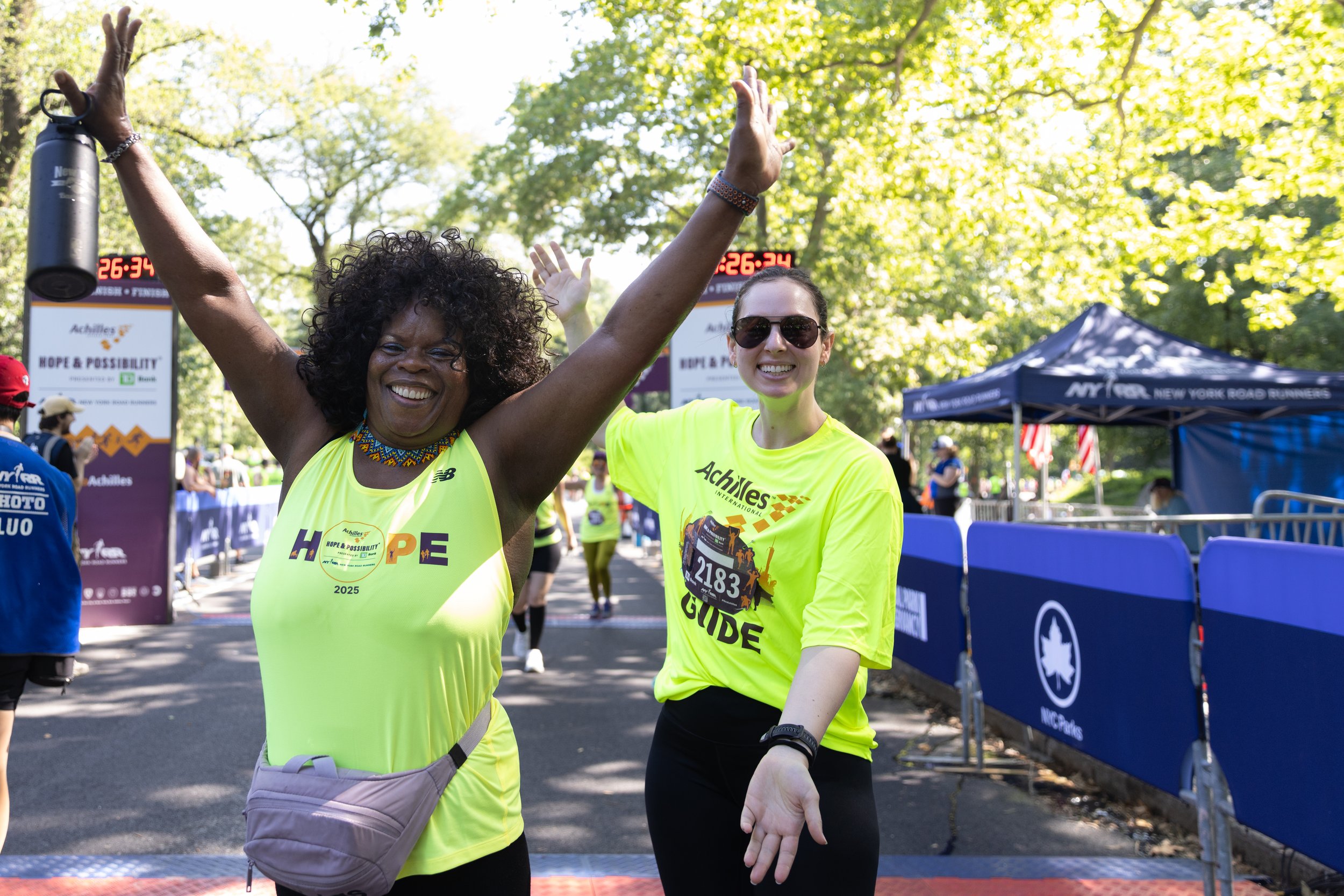 Achilles athlete posing with her guide after crossing the finish line.