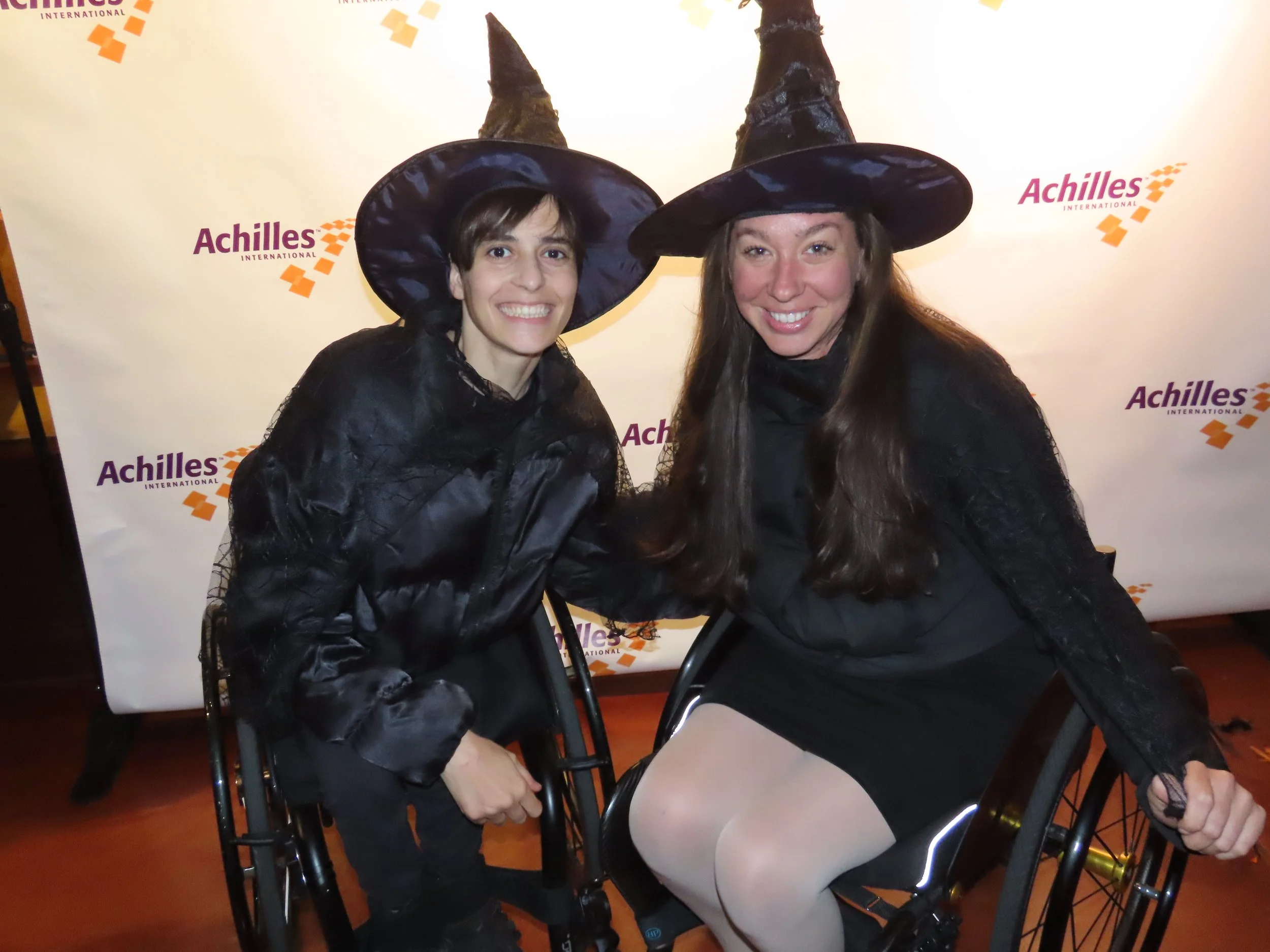  Achilles members in front of an Achilles branded step and repeat.  