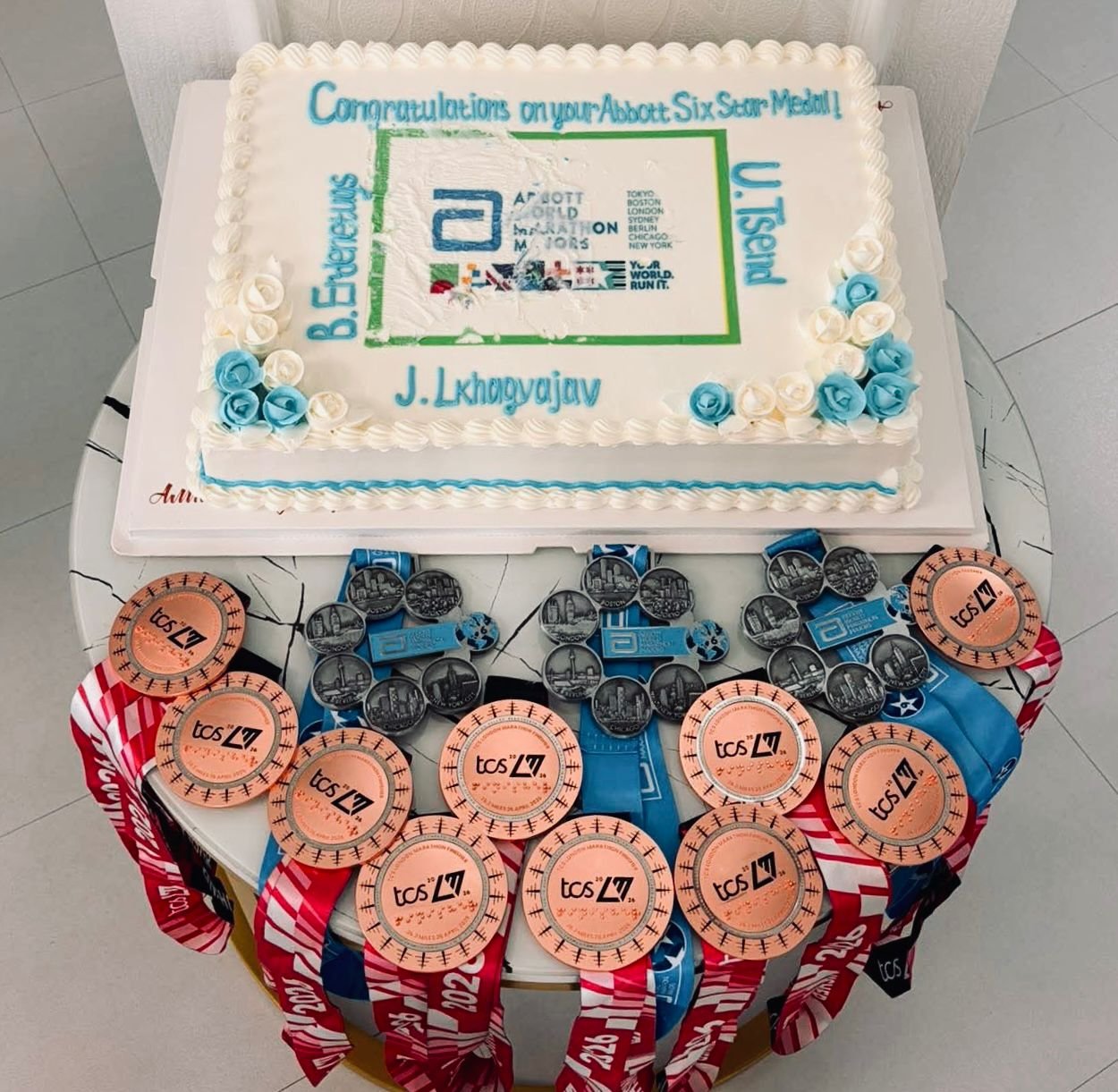  A cake surrounded by London Marathon medals and Abbott World Marathon majors Six Star Medals celebrating athletes from Achilles Mongolia who completed the race.  