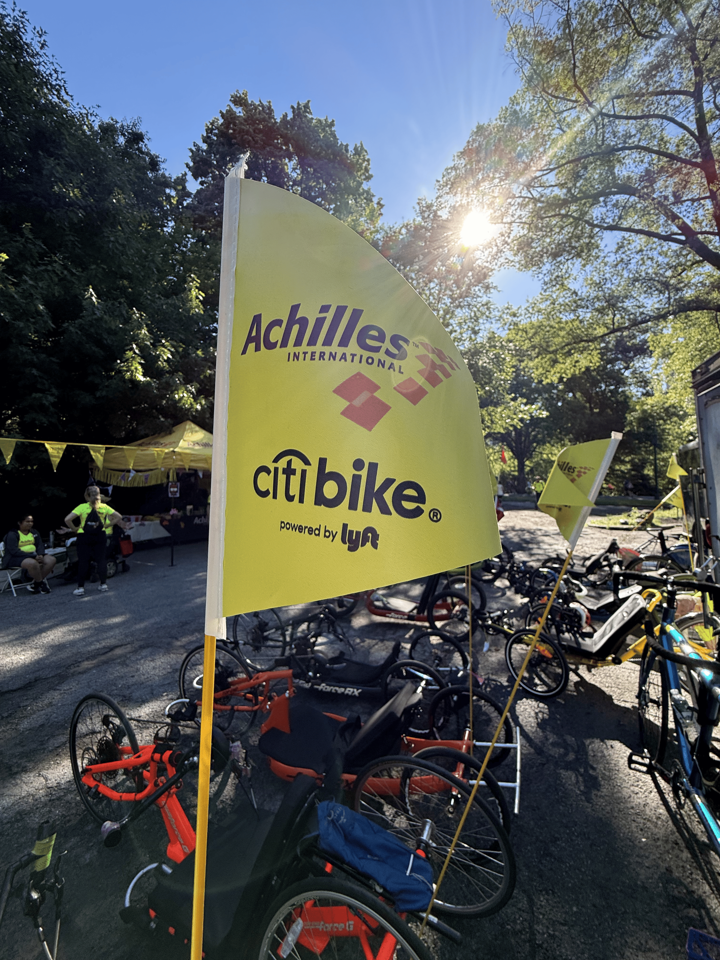  Photo of the Achilles x CitiBike powered by Lyft flag flying on the back of a handcycle.  