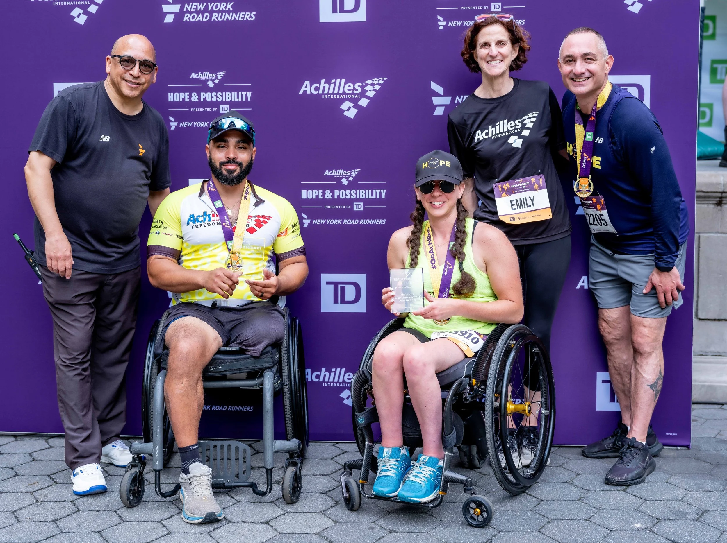  First place handcycle winners posing with their awards and leadership from Achilles, TD and New York Road Runners.  