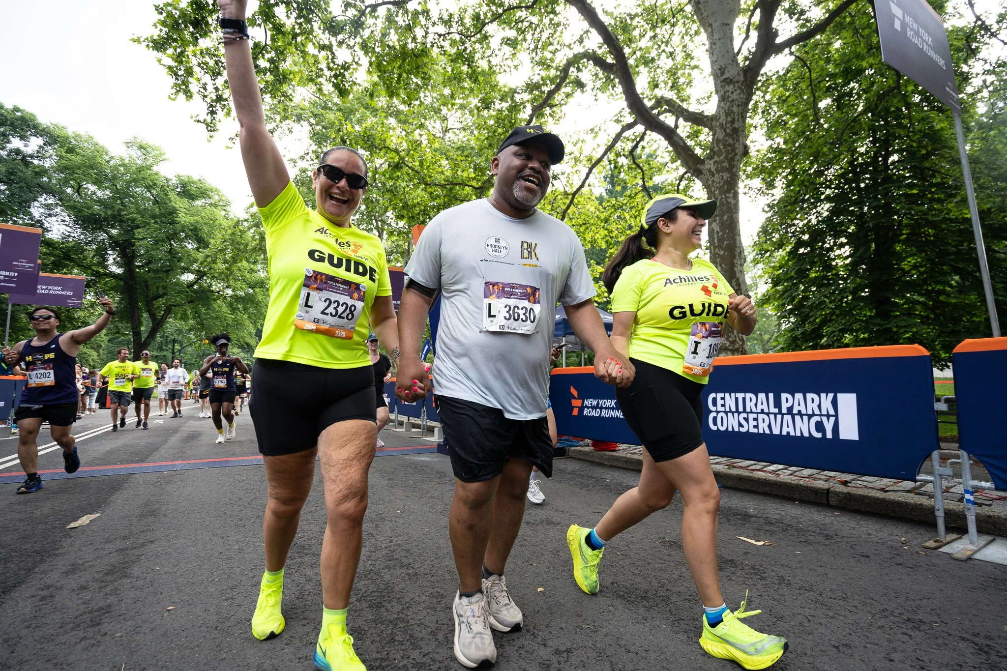  Achilles athlete smiling on the course with his two guides.  