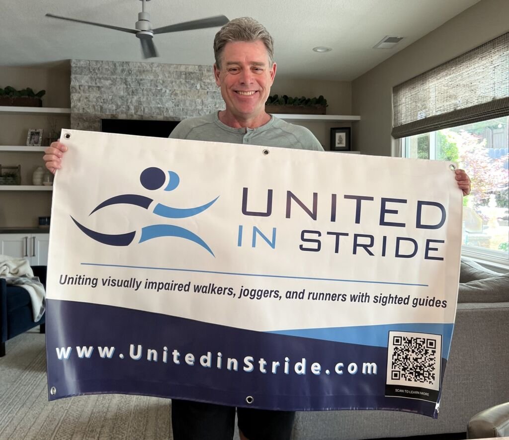 Richard Hunter smiling while holding up a United in Stride banner.