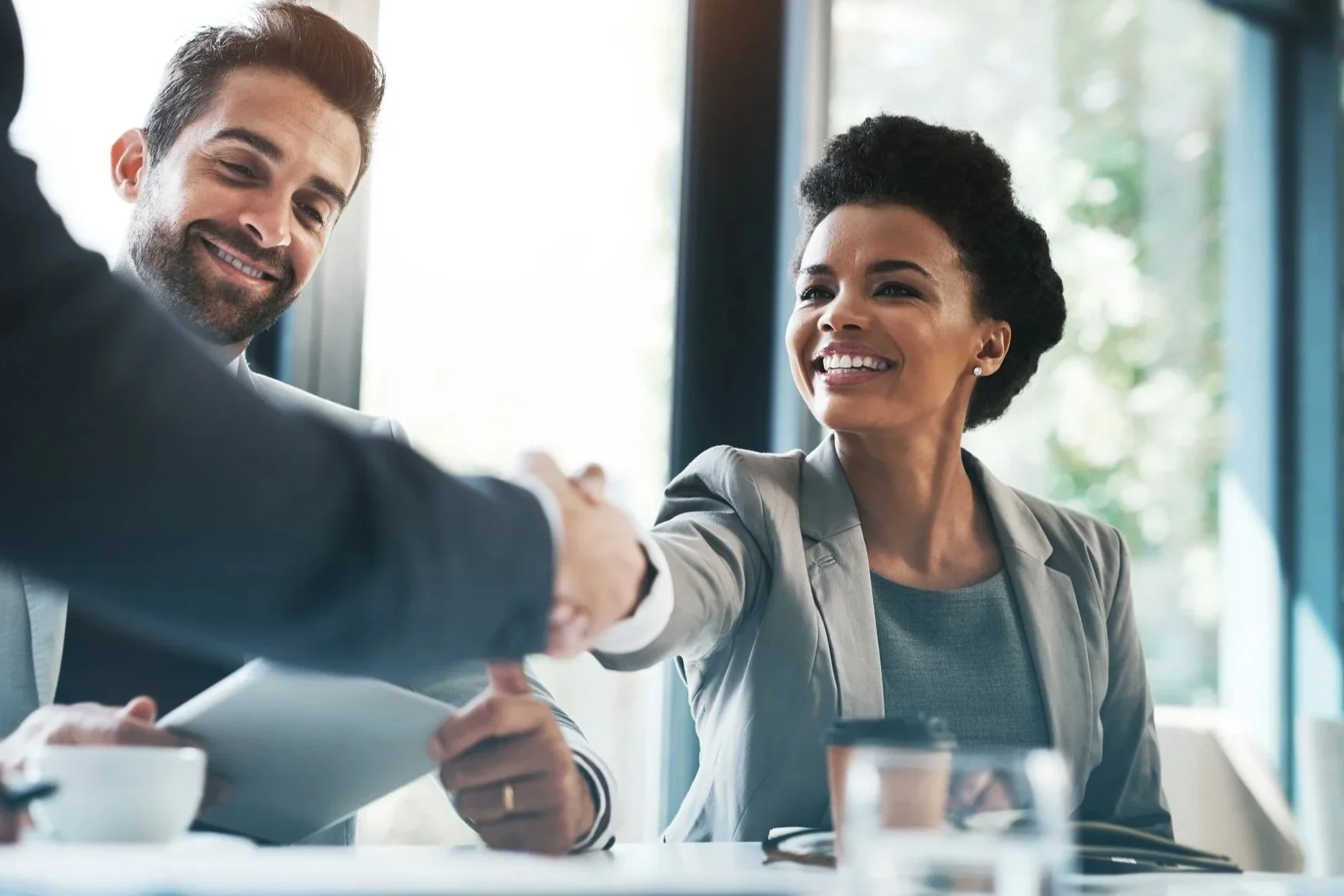 Professional woman confidently shaking hands in a business meeting, symbolizing career reentry and leadership.