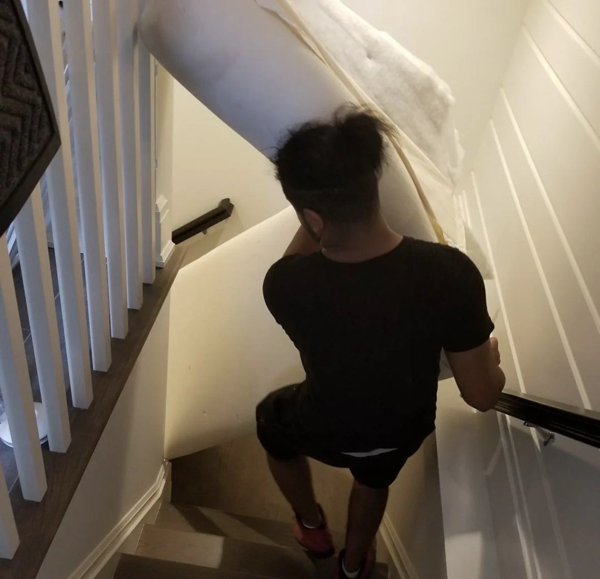 Large upholstered furniture being moved through a narrow staircase after disassembly.