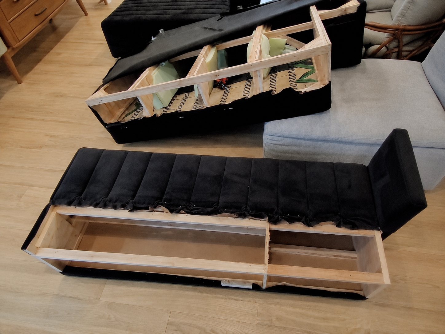 Black modular seating disassembled to reveal its internal wooden frame, springs, foam and upholstery