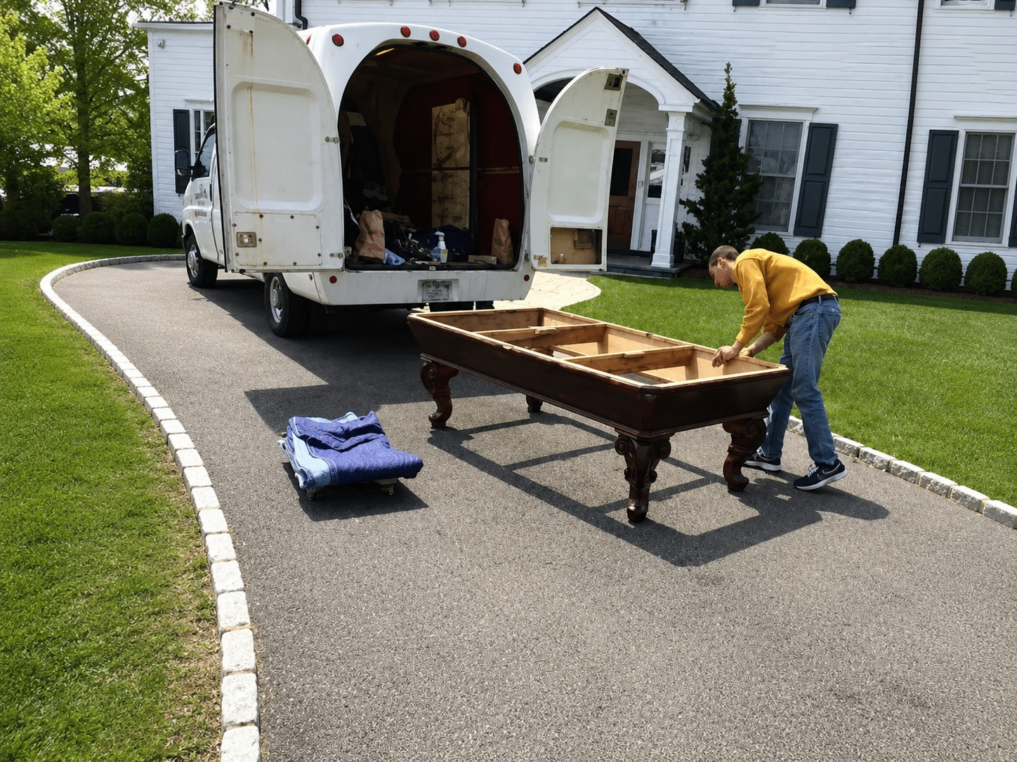 Technician preparing the exposed wooden frame of a disassembled pool table beside the moving truck