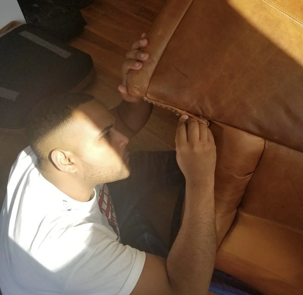 Z Brothers technician examining a leather sofa before furniture disassembly.