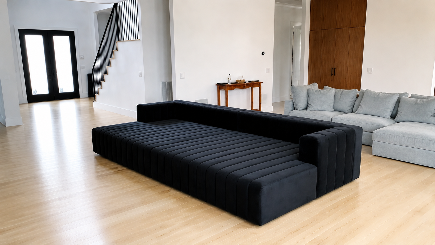 Full view of oversized black channel-tufted modular seating professionally reassembled in a modern home