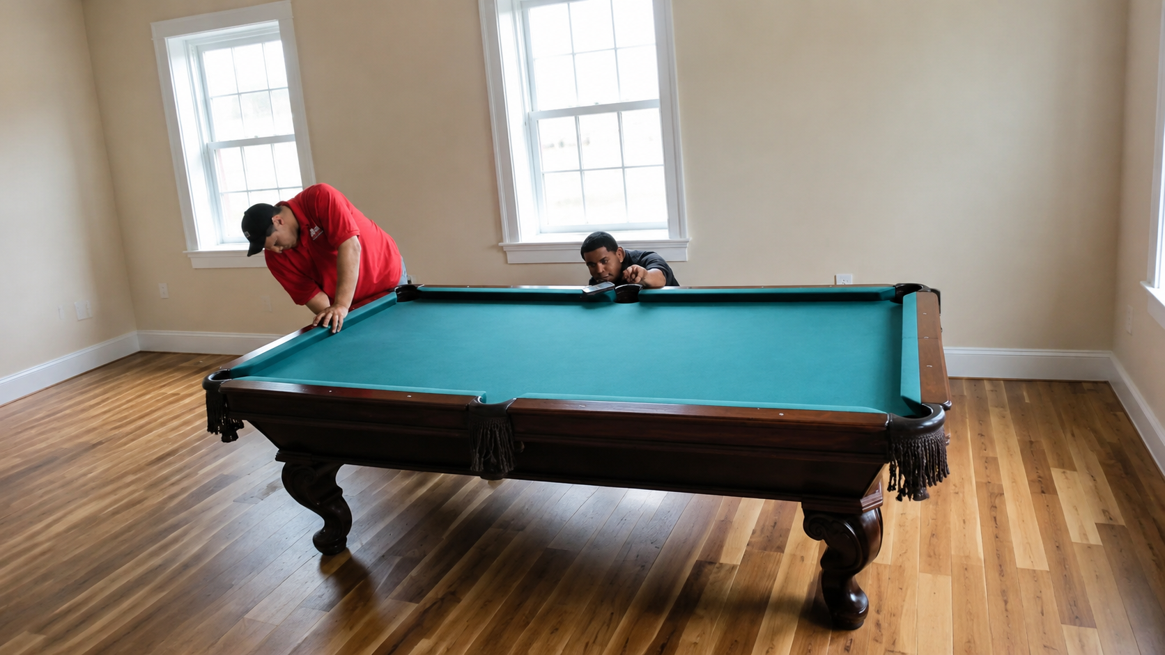 Traditional dark wood pool table with green felt professionally reassembled and leveled by two technicians