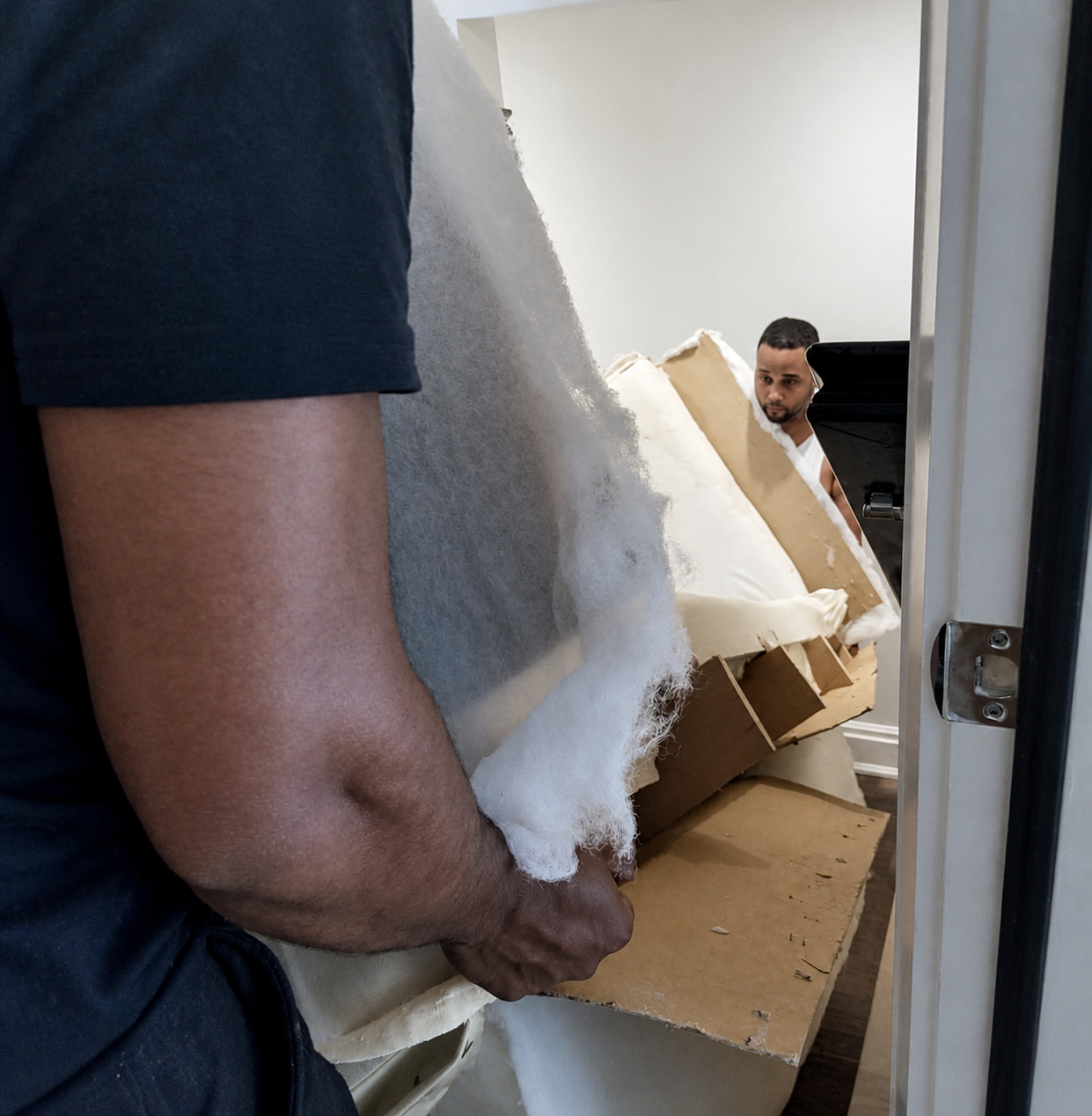 Professionally disassembled sofa being carried through a tight doorway.