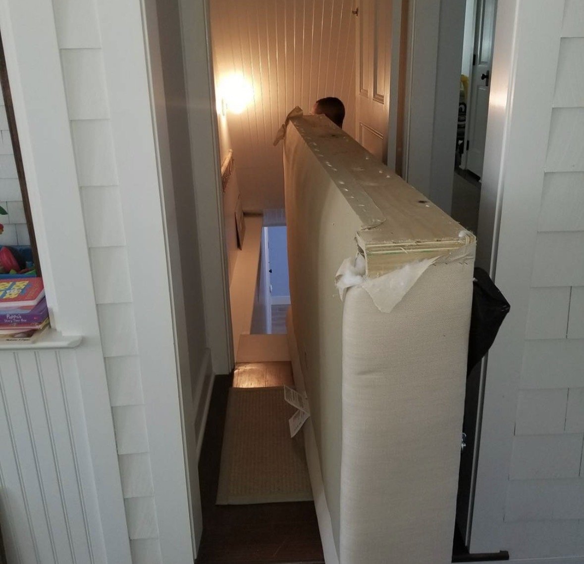 Z Brothers technician moving a disassembled sofa through a narrow doorway and staircase