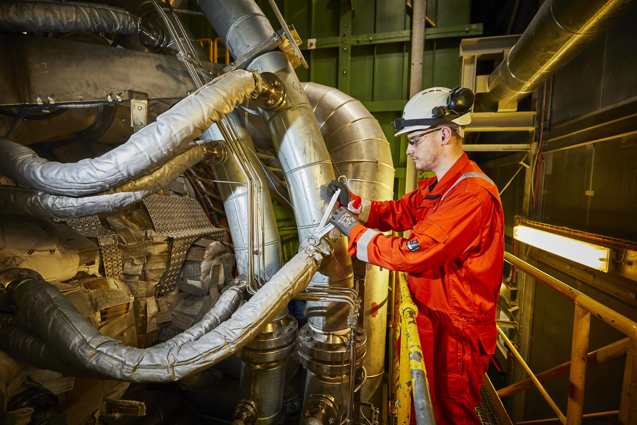 Worker in orange overalls repairing pipes at a power station