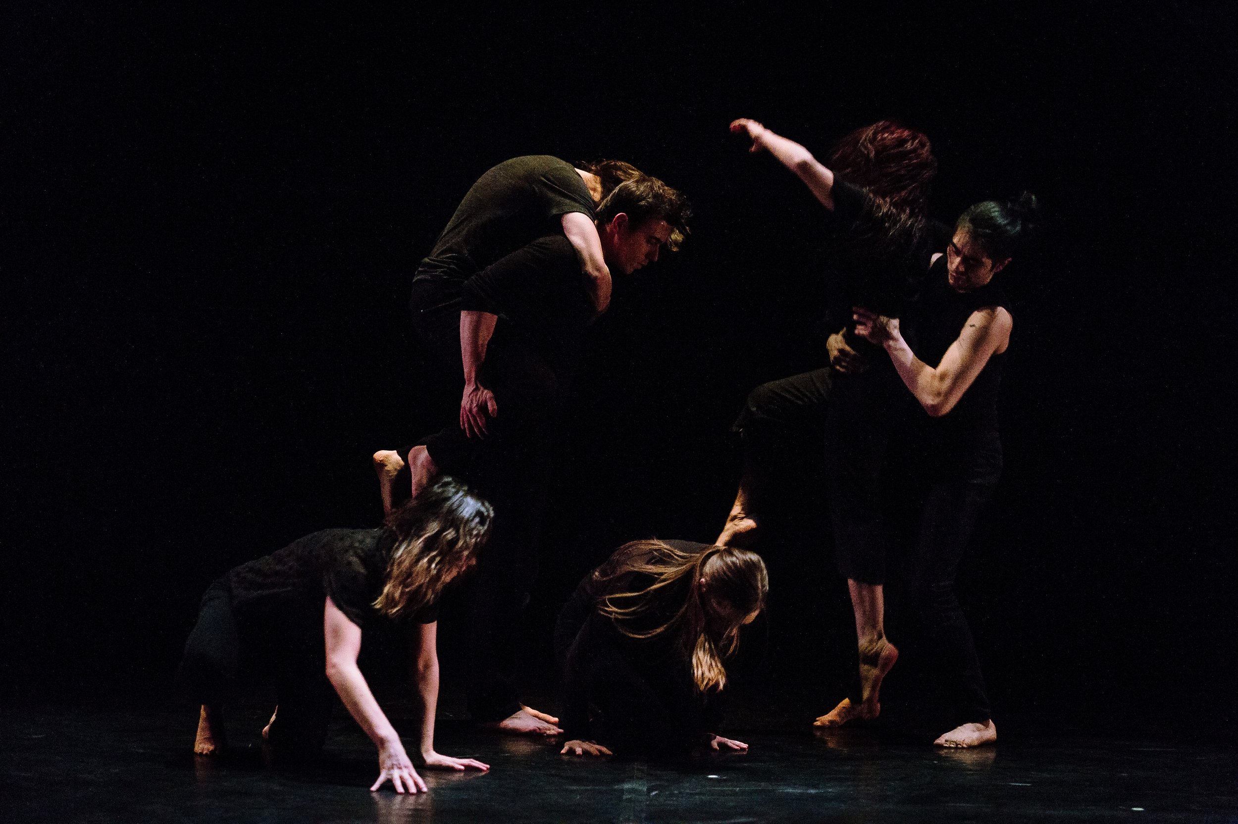 A group of dancers on various levels – some crawling, some lifted into the air.