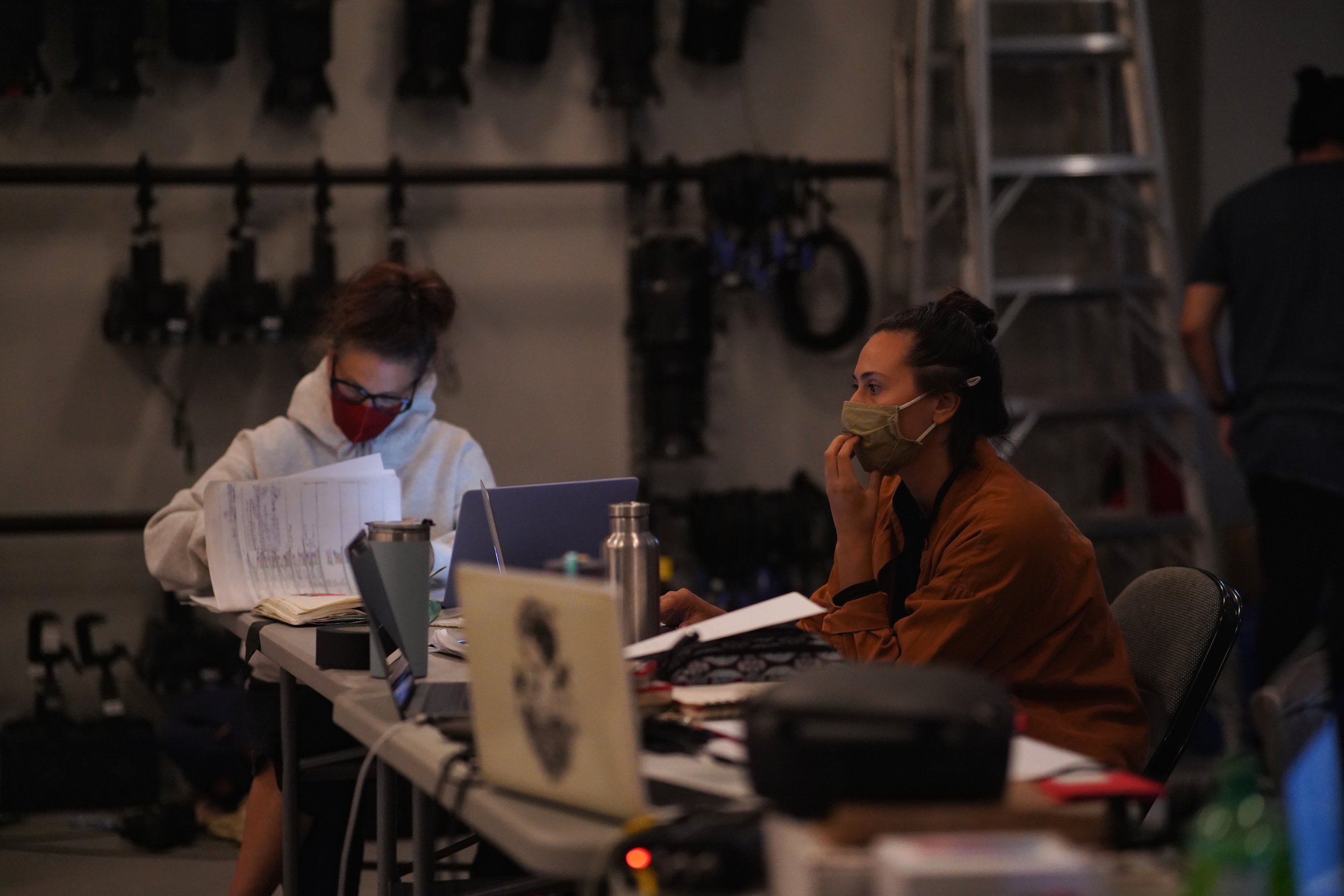 Karen Kaeja and Aria Evans at a table covered with laptops and papers.