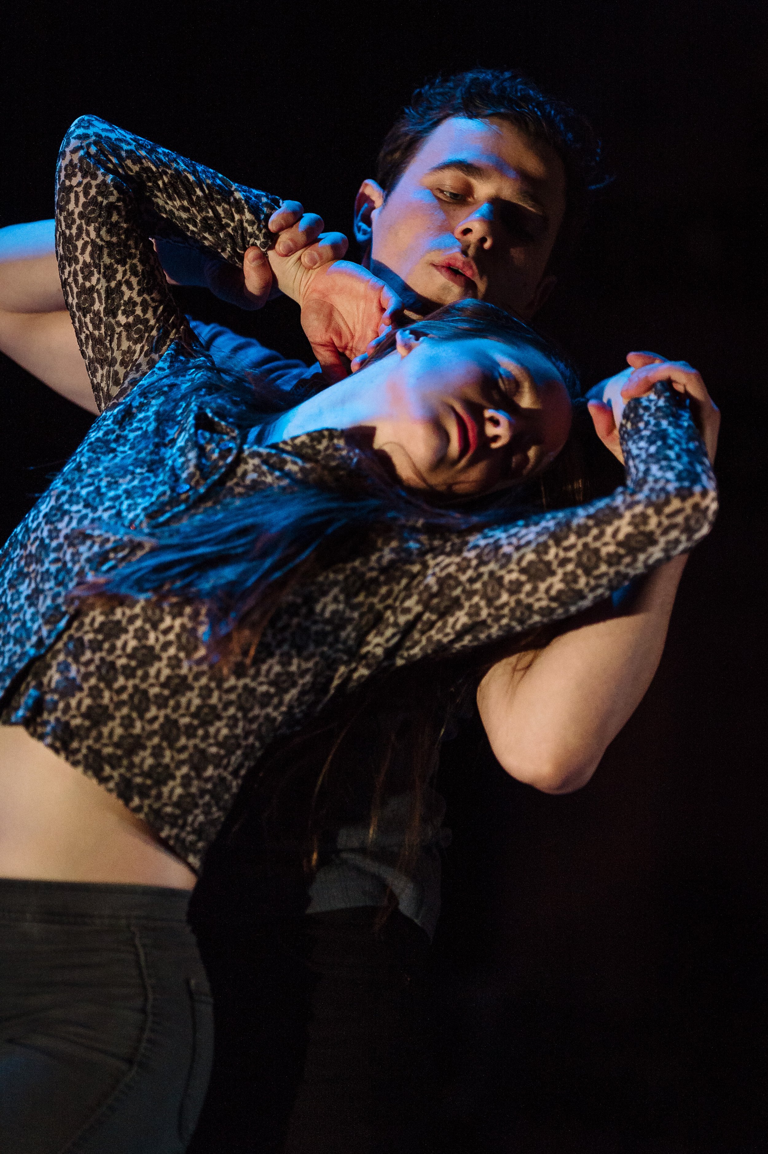 One dancer leans back into another with their arms beside their head.