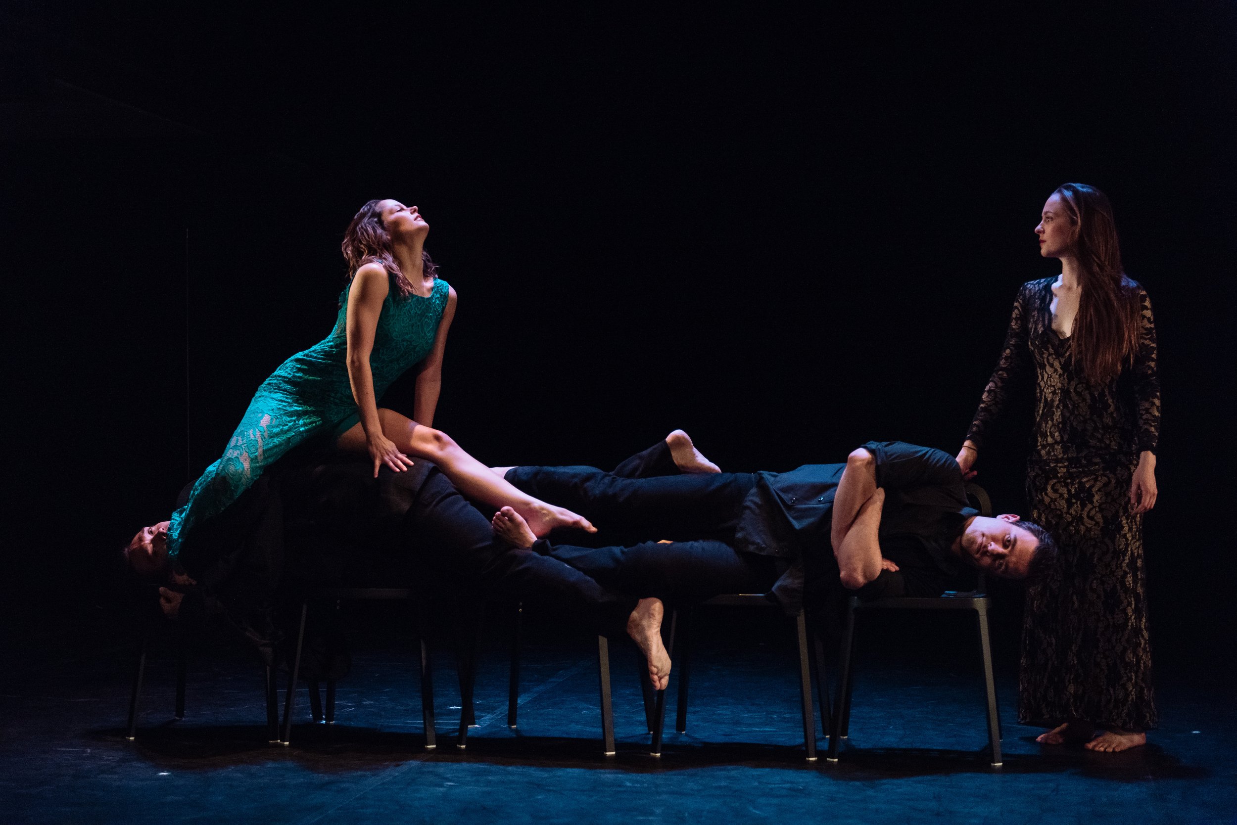 Several dancers lay across several chairs.
