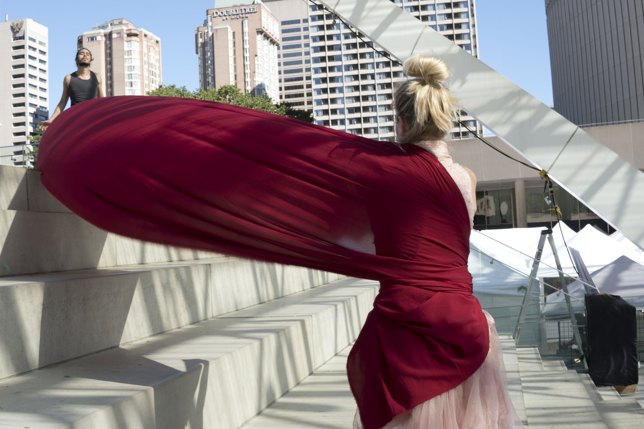 A dancer's back wrapped in red fabric that billows out to one side of them.